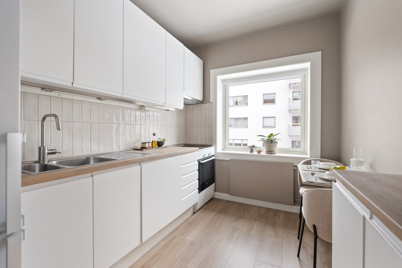 Hvit innredning med glatte, laminerte skapfronter og en heltre benkeplate som gir et varmt og tidløst uttrykk. Galleribilde