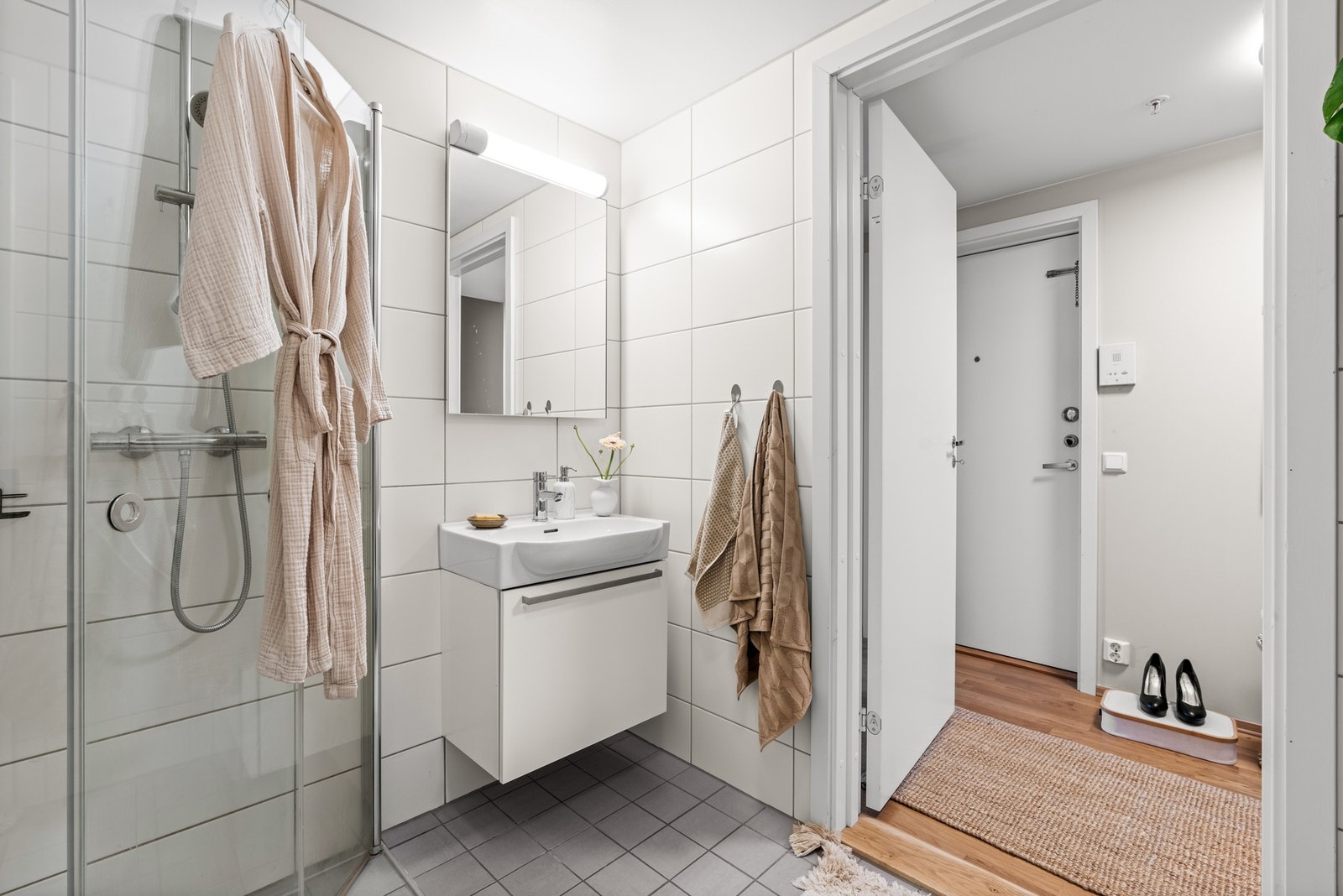 Leiligheten har et pent, flislagt bad med inngang fra entréen Galleribilde