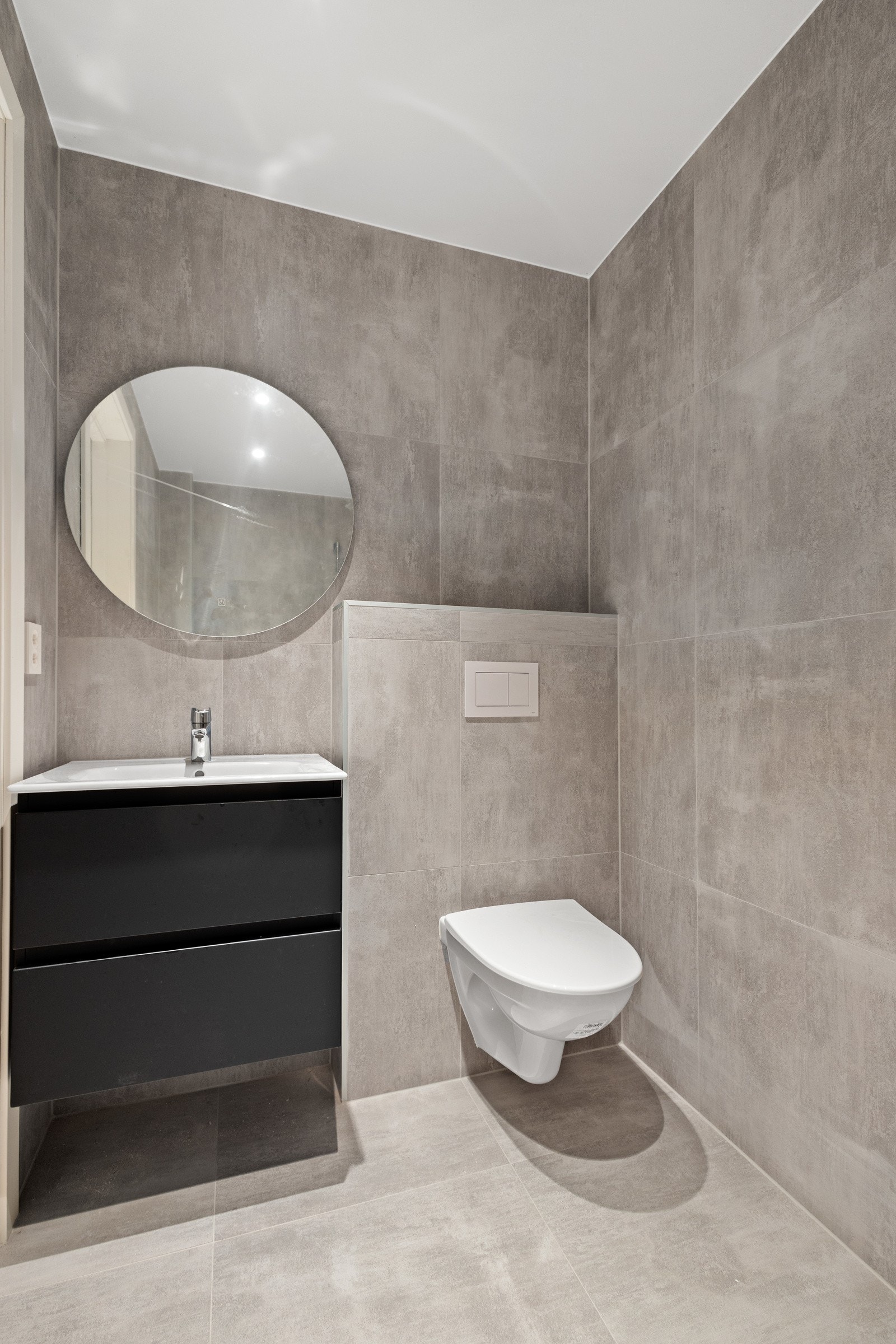 Delikat, flislagt baderom innredet med dusj, servant med skuffeseksjon og klosett. Galleribilde