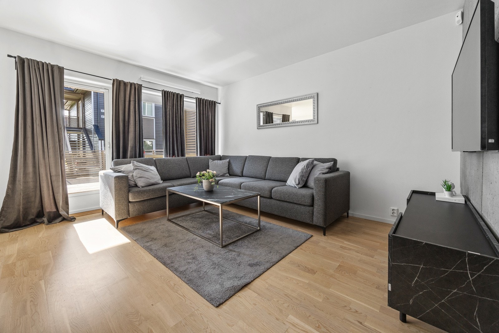 Den åpne stuen fremstår som meget innbydende i lyse, delikate fargevalg i kombinasjon med to kontrastvegger belagt med moderne betongplater. Gode vindusflater slipper inn rikelig med lys og gir en luftig romfølelse. Galleribilde