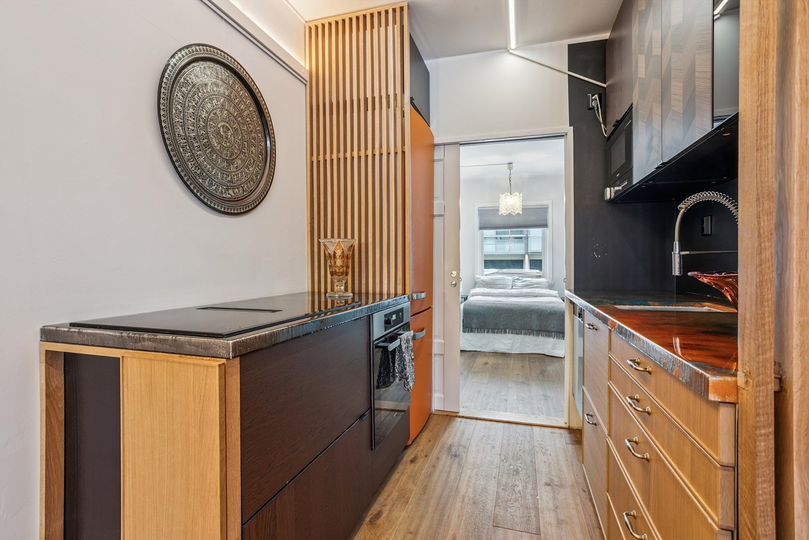 Kjøkkenet har over- og underksap, kjøleskap/frys, oppvaskmaskin, stekeovn/steketopp og mikrobølgeovn. Det er laminert benkeplate som er farget og dekket av epoxy/resin. Fra kjøkkenet er det inngang til soverom Galleribilde