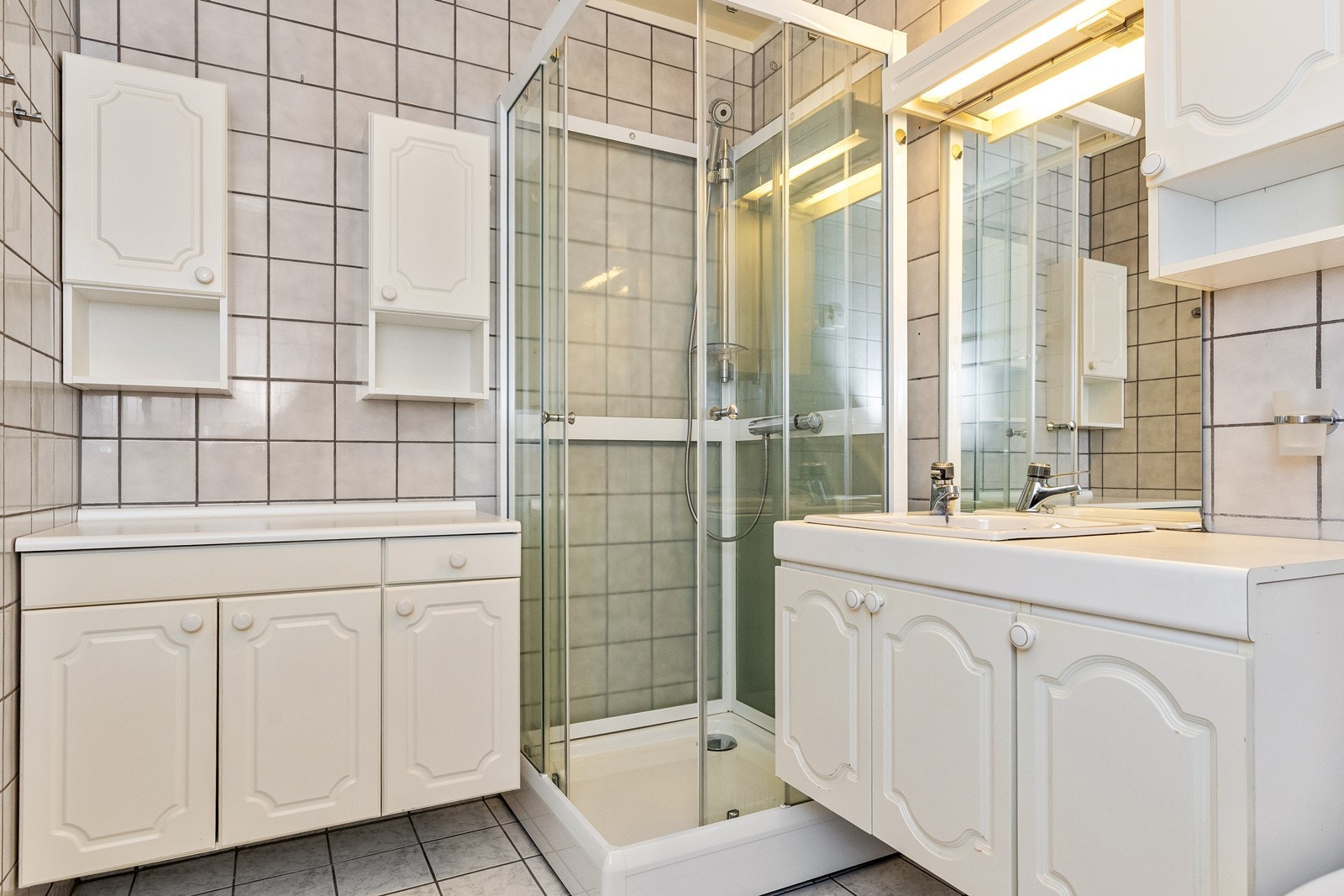 Badet har flislagte overflater på gulv og vegg, varmekabler i gulv. Her finner du en baderomsinnredning med skuffer, servant, speil og et tilhørende sideskap som gir gode oppbevaringsmuligheter. Galleribilde