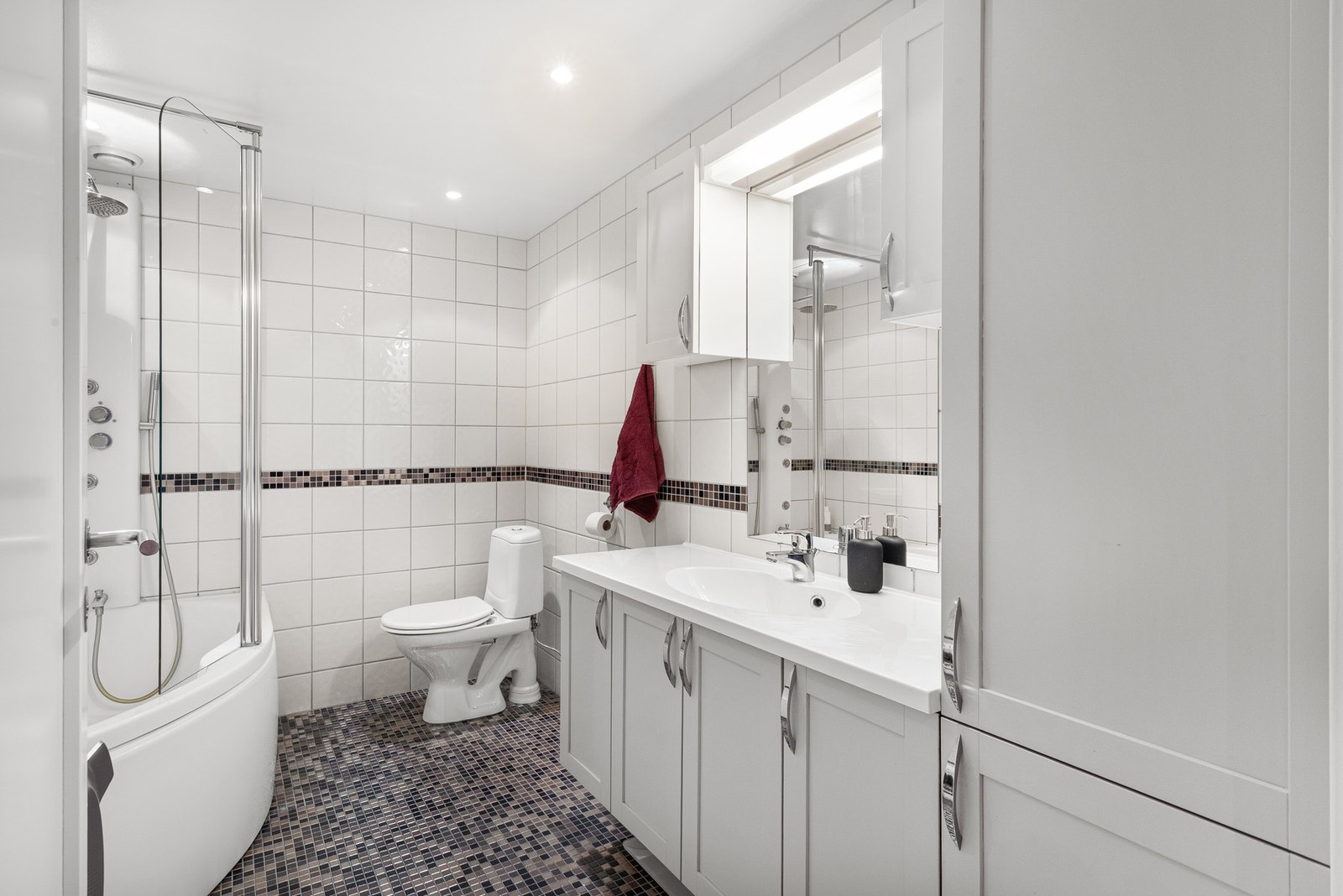 Flott baderom med boblebad/dusj, toalett, servant med underskap, speil og overskap. Galleribilde