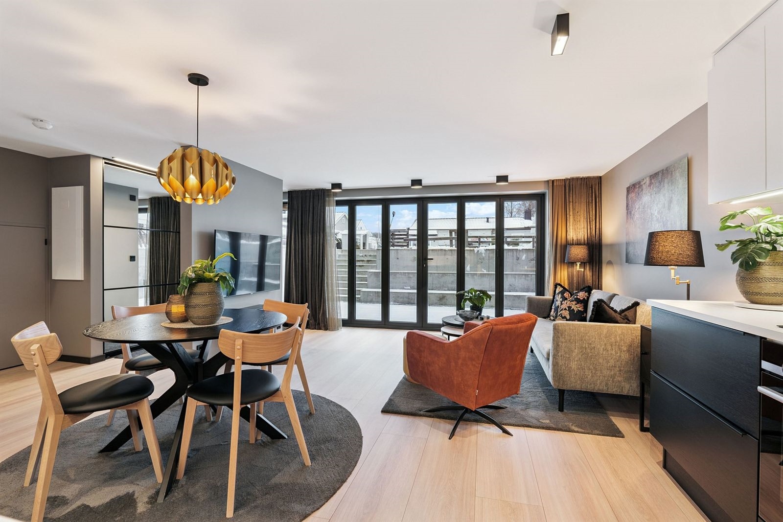 Stor og lys stue med åpen kjøkkenløsning, store foldedører som sikrer godt med naturlig belysning og tar deg ut til en 23 kvm privat uteplass. Galleribilde