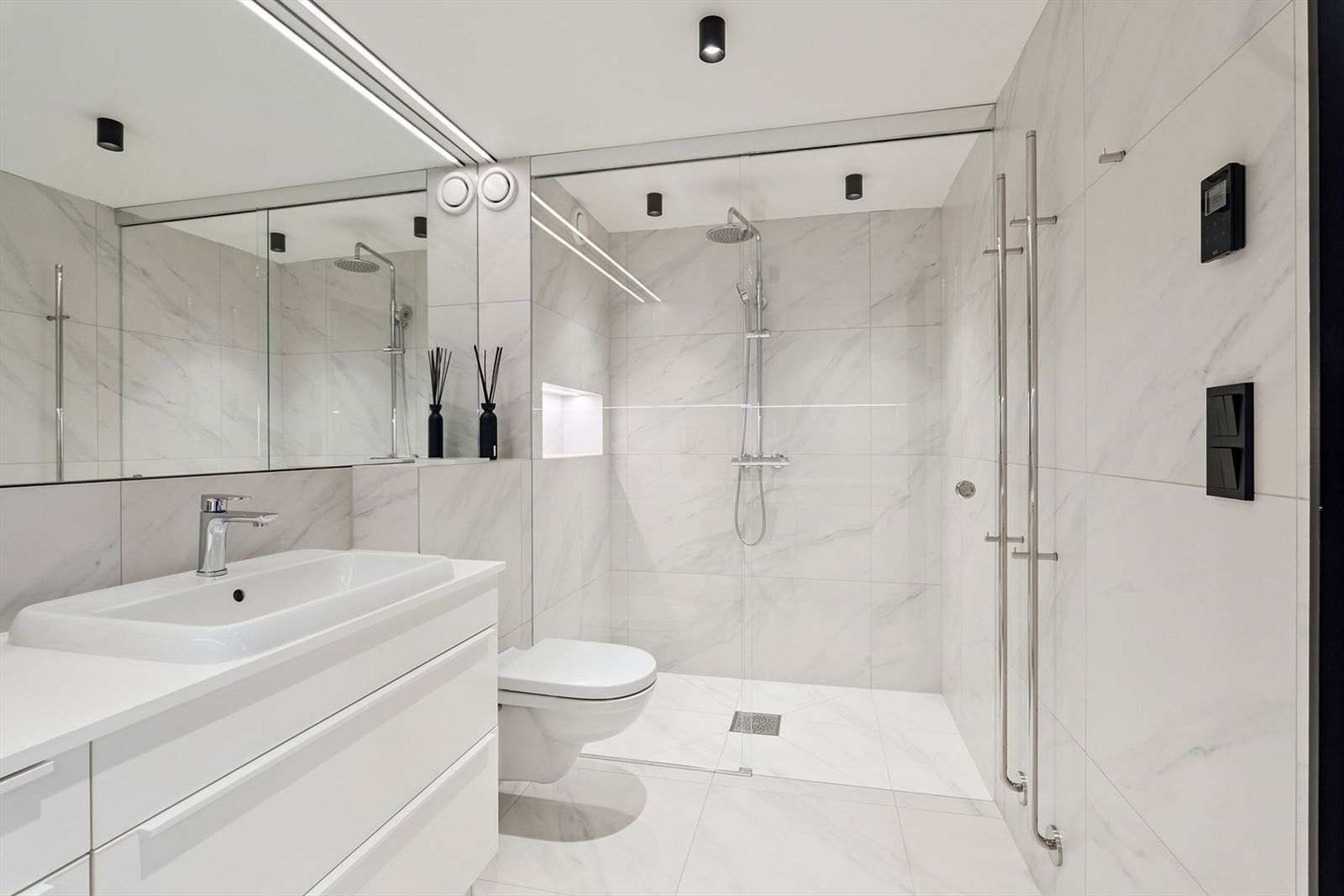 Stort bad som gir deg en skikkelig hotellfølelse. Stor dusjnisje, store speiloverflater og fliser på gulv og vegger i marmorfinish. Galleribilde