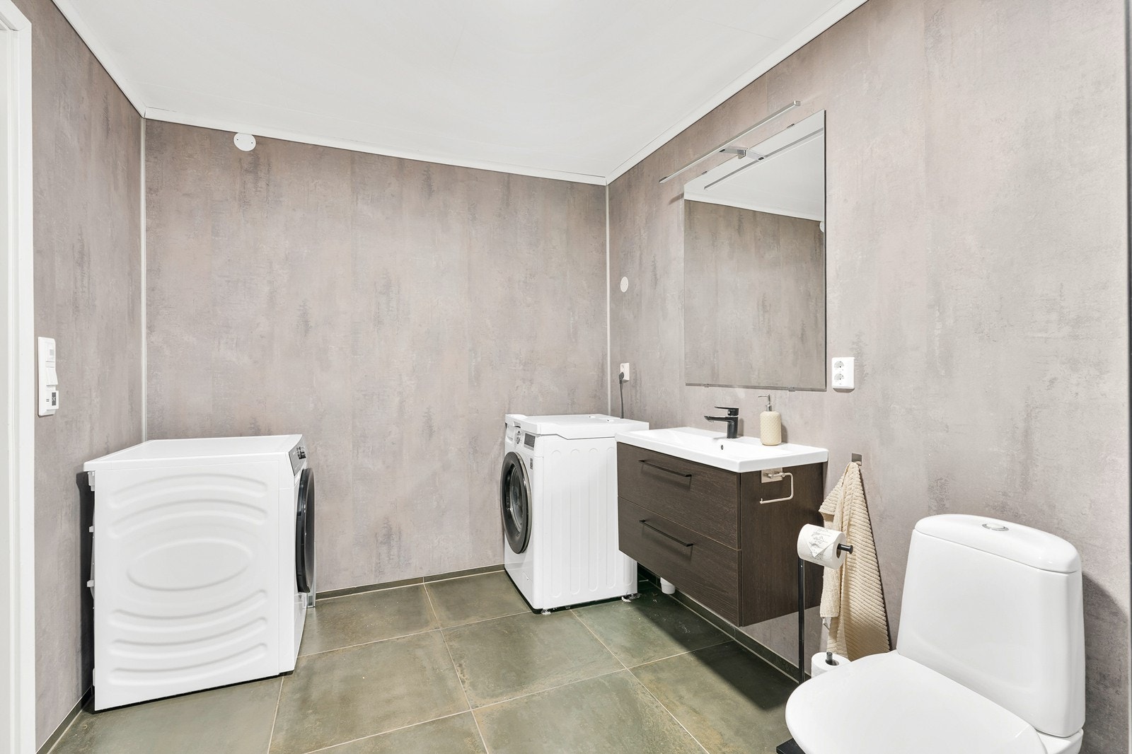 Badet er innredet med gulvstående toalett, servant med skuffeinnredning, speil samt dusj med glassvegger. Galleribilde