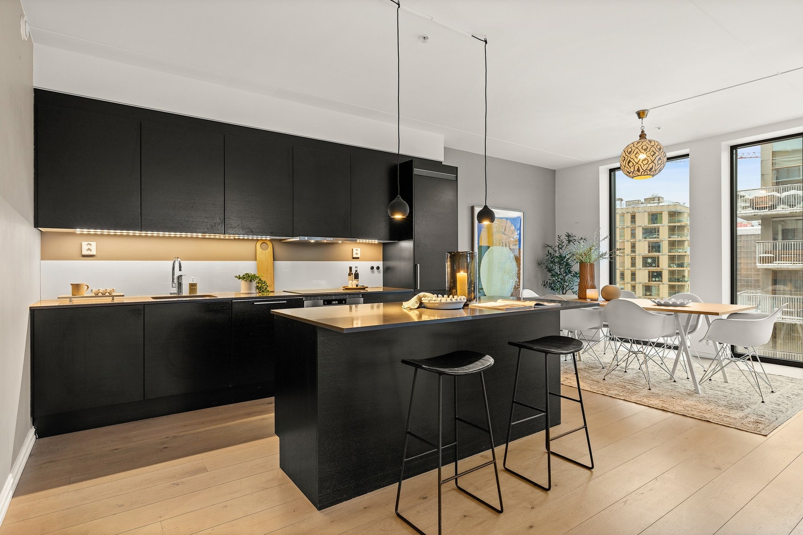 Kjøkkeninnredningen har glatte fronter, benkeplater i stein og nedfelt kum av stål Galleribilde