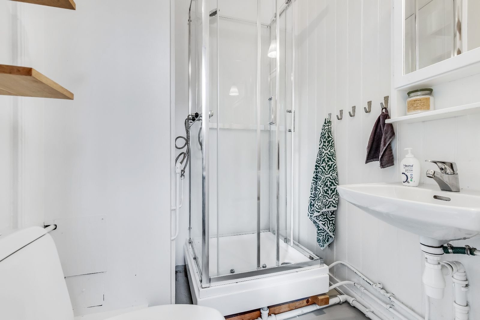 Lyst bad av enkel standard med wc, dusjkabinett og servant med speilskap Galleribilde