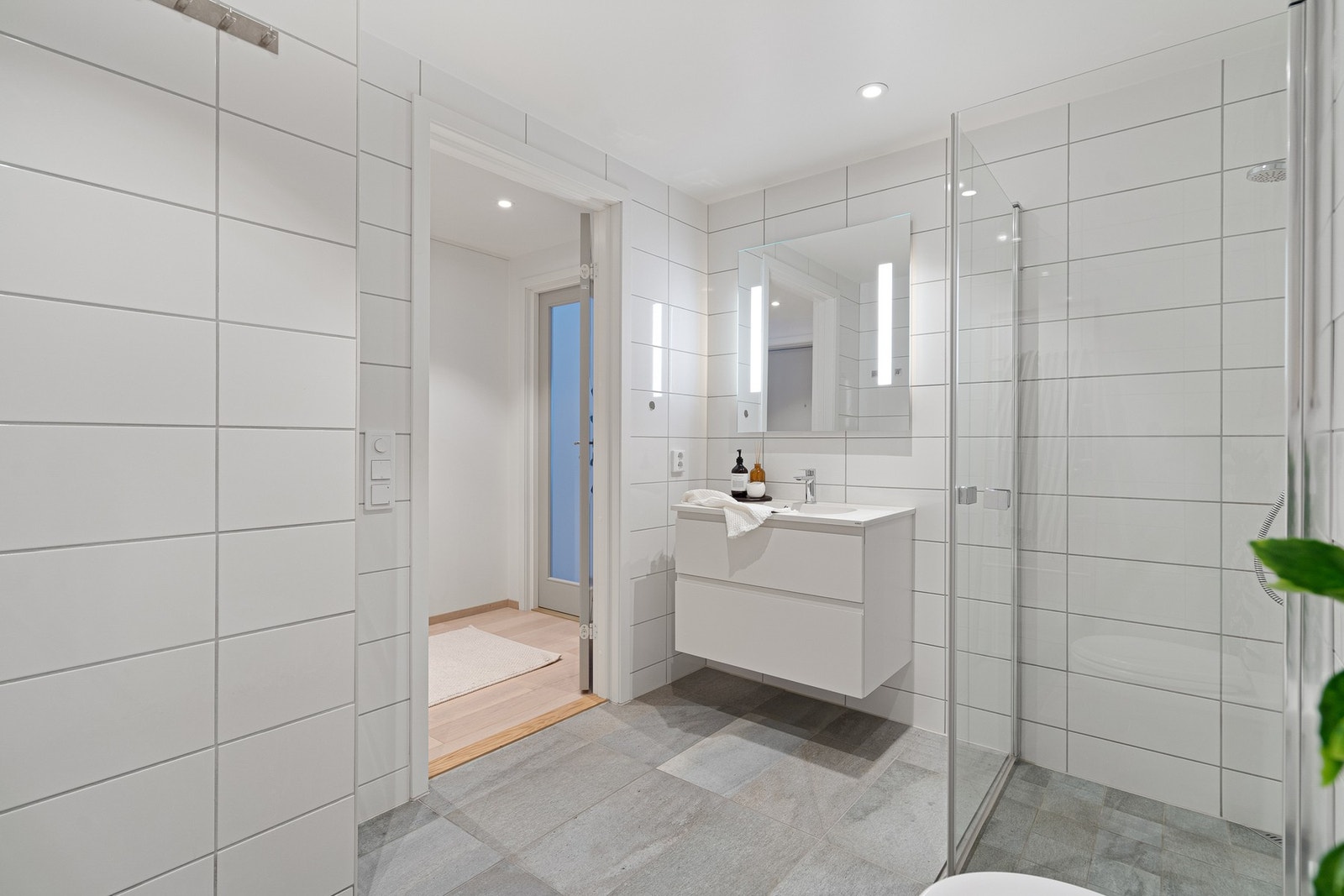 Det er utstyrt med servant med innredning, veggmontert toalett, dusjløsning og opplegg for vaskemaskin, et pent og funksjonelt bad tilpasset hverdagen. Galleribilde