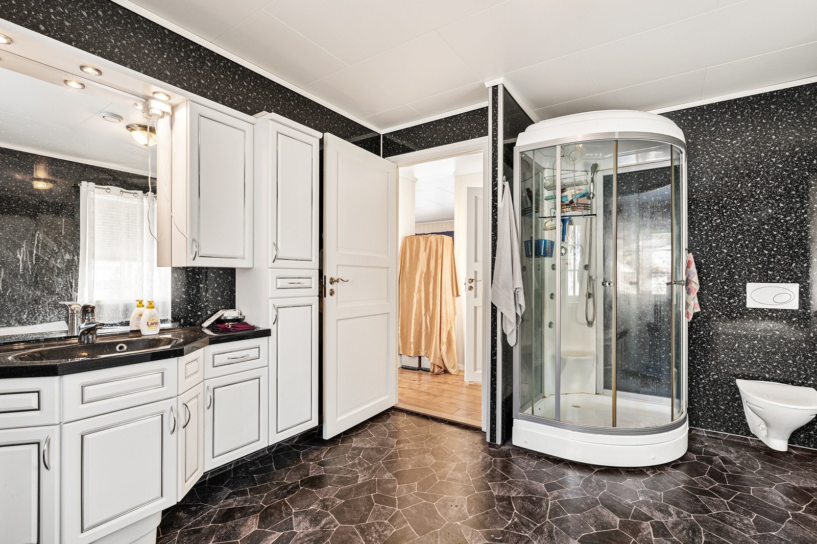 Romslig bad som er innredet med servant, badekar, dusjkabinett og vegghengt toalett. Galleribilde