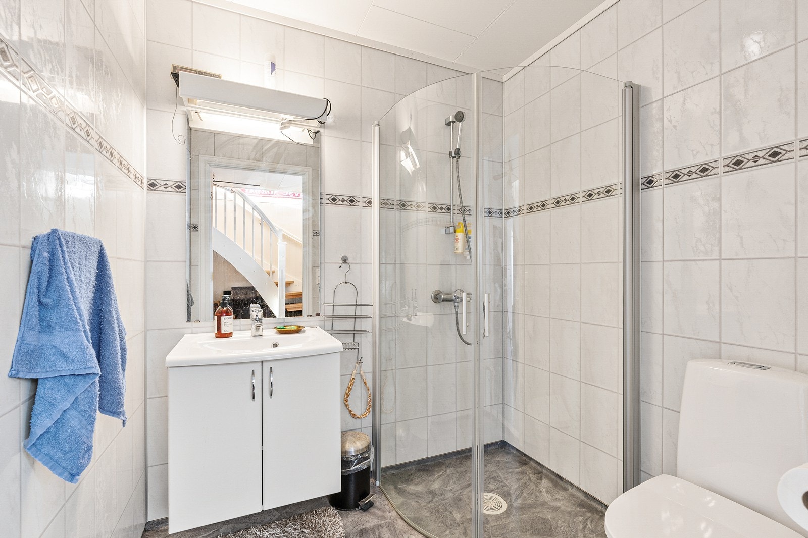 Lyst og pent bad med gulvbelegg med varmekabler, baderomsplater på vegger, innredet med dusjhjørne med vendbare glassvegger, toalett og baderomsinnredning med servant. Galleribilde