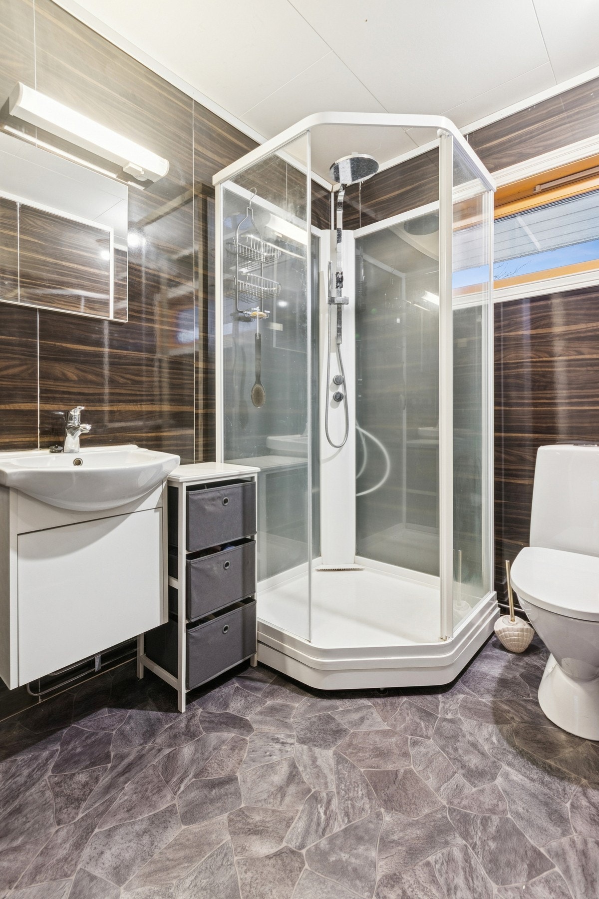 Badet er utstyrt med baderomsplater på vegger, vinylbelegg på gulv, himlingsplater i tak, elektriske varmekabler samt innredning med nedfelt servant, toalett og dusjkabinett. Galleribilde