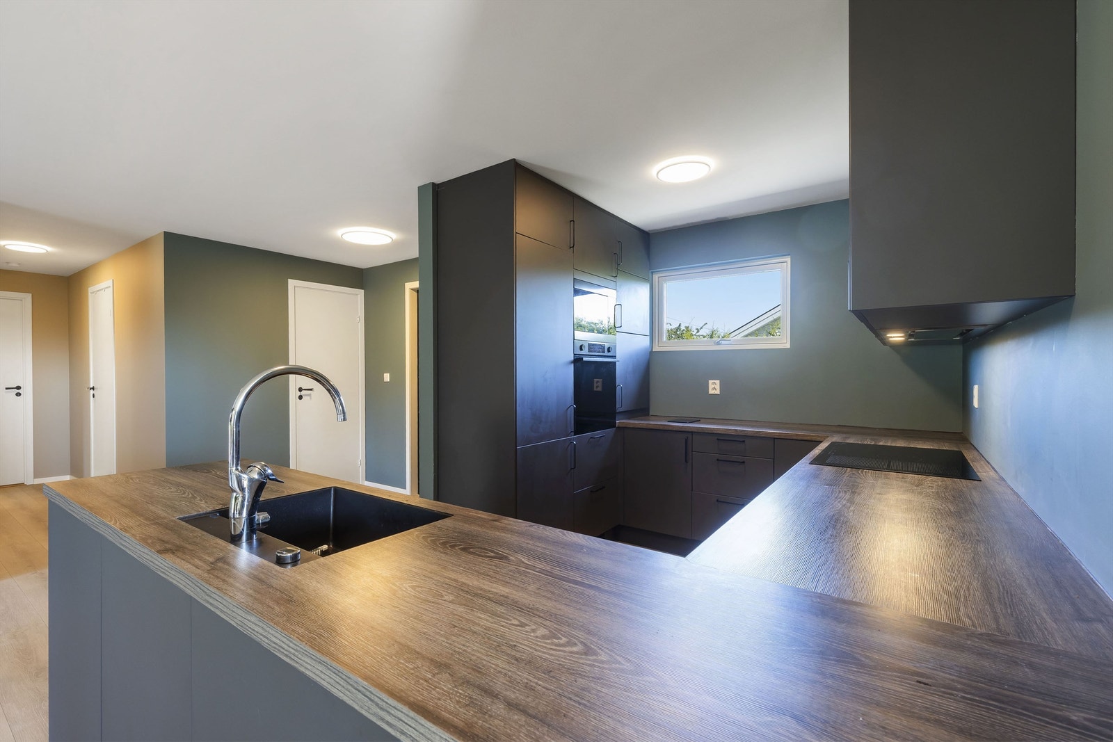 Lekkert kjøkken med slette sorte fronter og laminat benkeplate Galleribilde