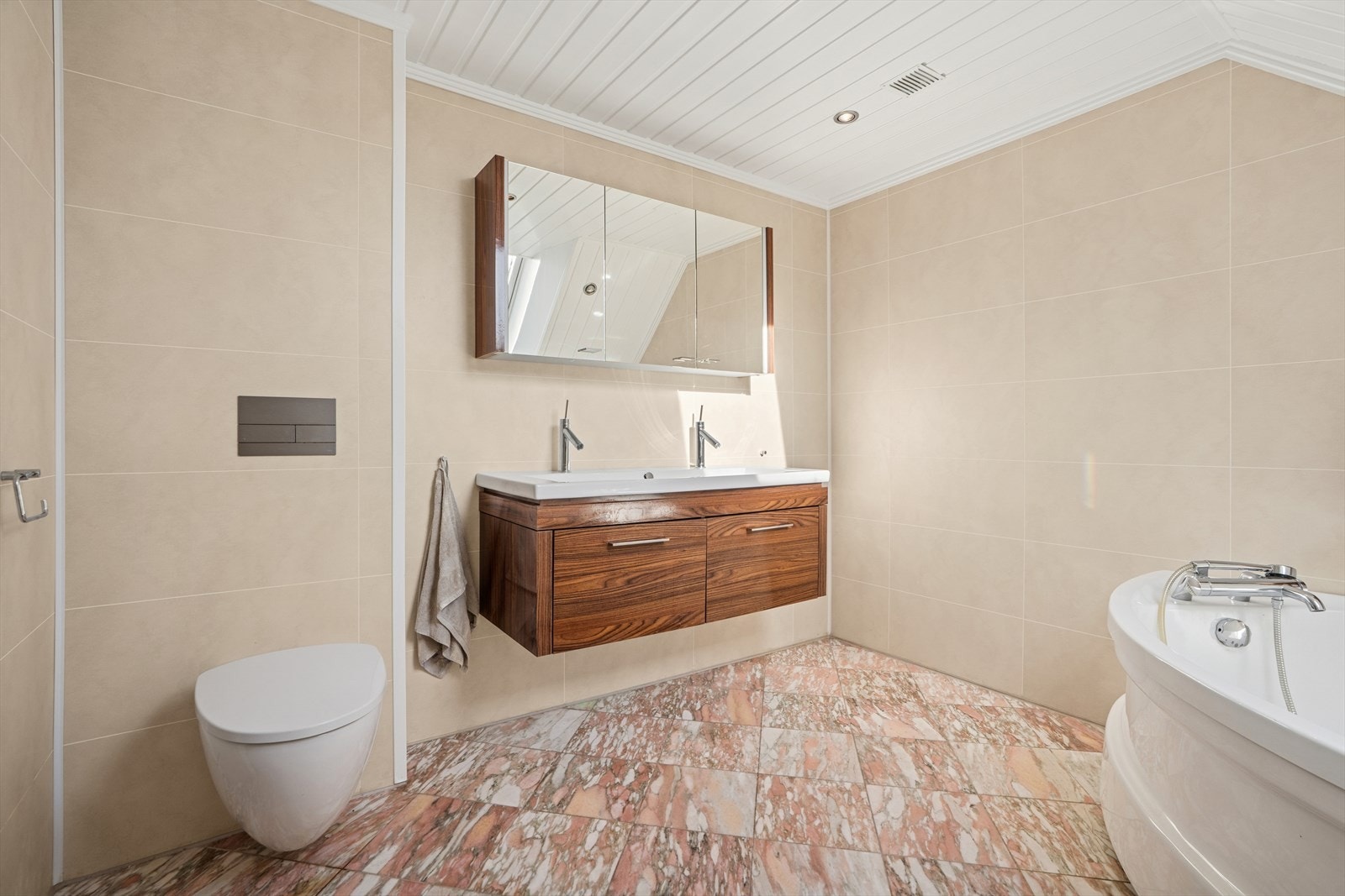 Badet er utstyrt med baderomsinnredning med servant og to blandebatterier, speilskap, lys, boblebadekar og vegghengt toalett. Ventilasjon via mekanisk avtrekk fra loftventilator. Galleribilde