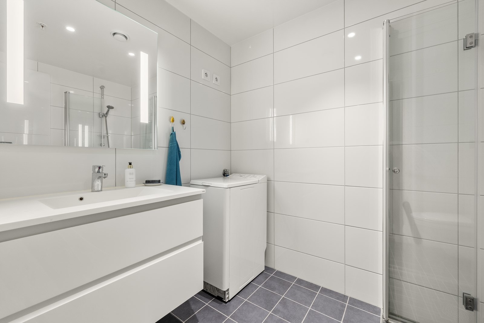 Badet er helfliset og utstyrt med servantmøbel, vegghengt toalett og opplegg for vaskemaskin. Galleribilde