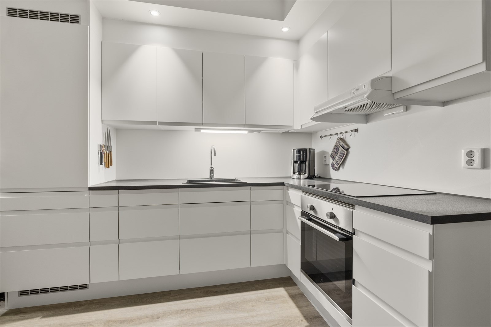 Kjøkkeninnredningen har slette, hvite fronter og en mørk laminatbenkeplate. Galleribilde