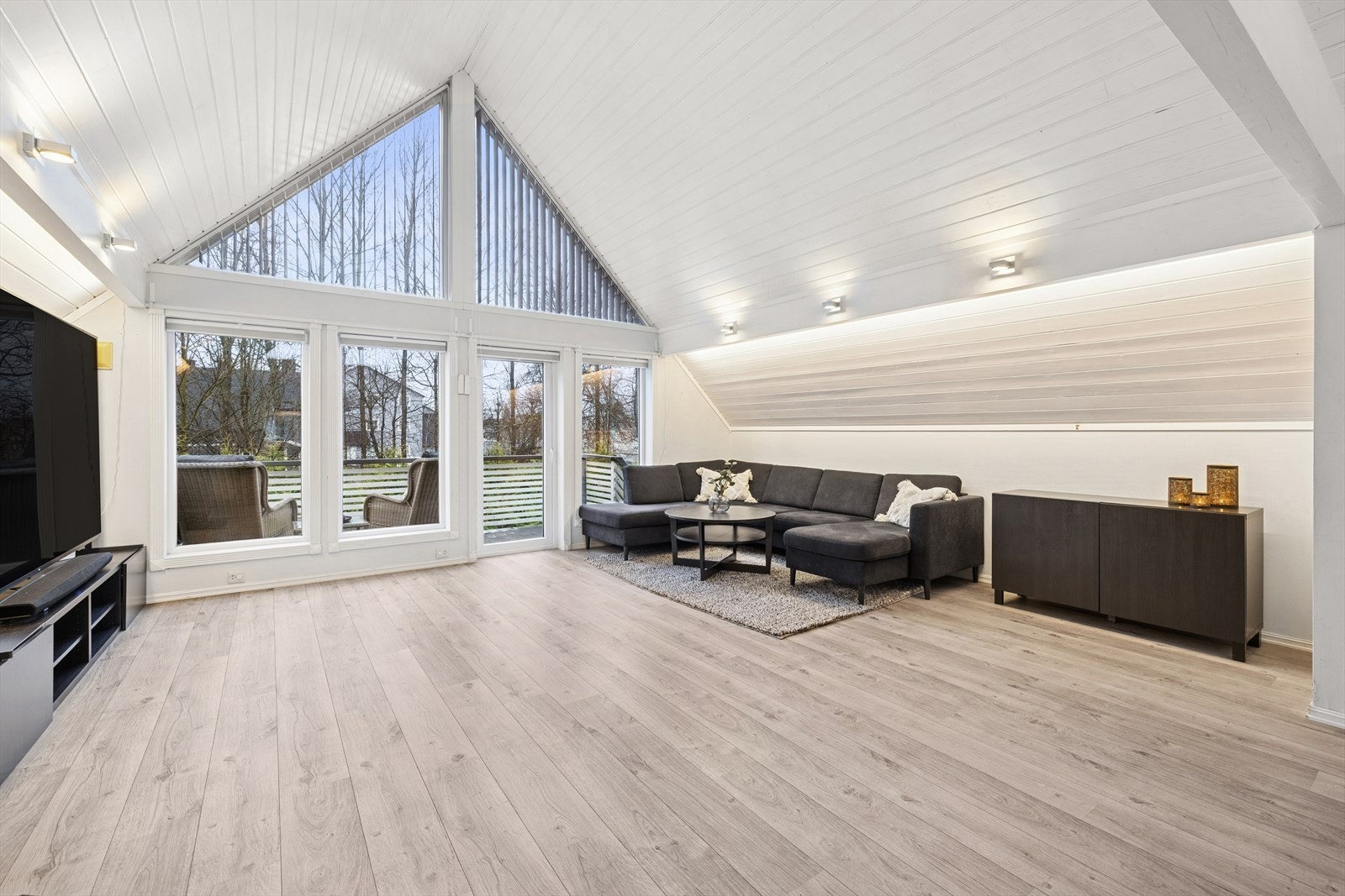 Stuen har store vindusflater som slipper inn godt med naturlig lys, og sammen med den gode takhøyden gir dette rommet en lys og luftig følelse. Galleribilde