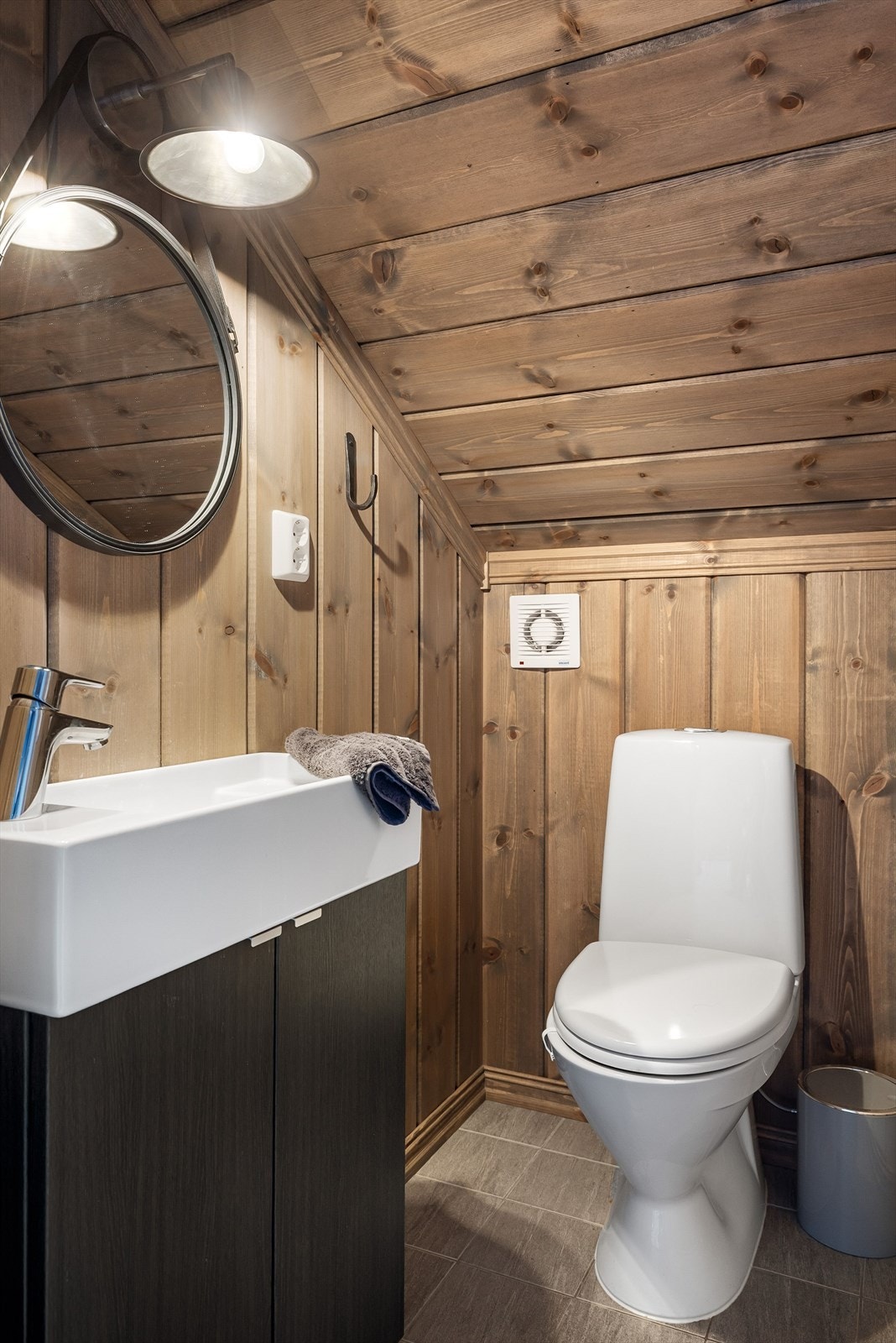 På hemsen er det et toalettrom med flislagt gulv, gulvmontert toalett og servant skap. Galleribilde