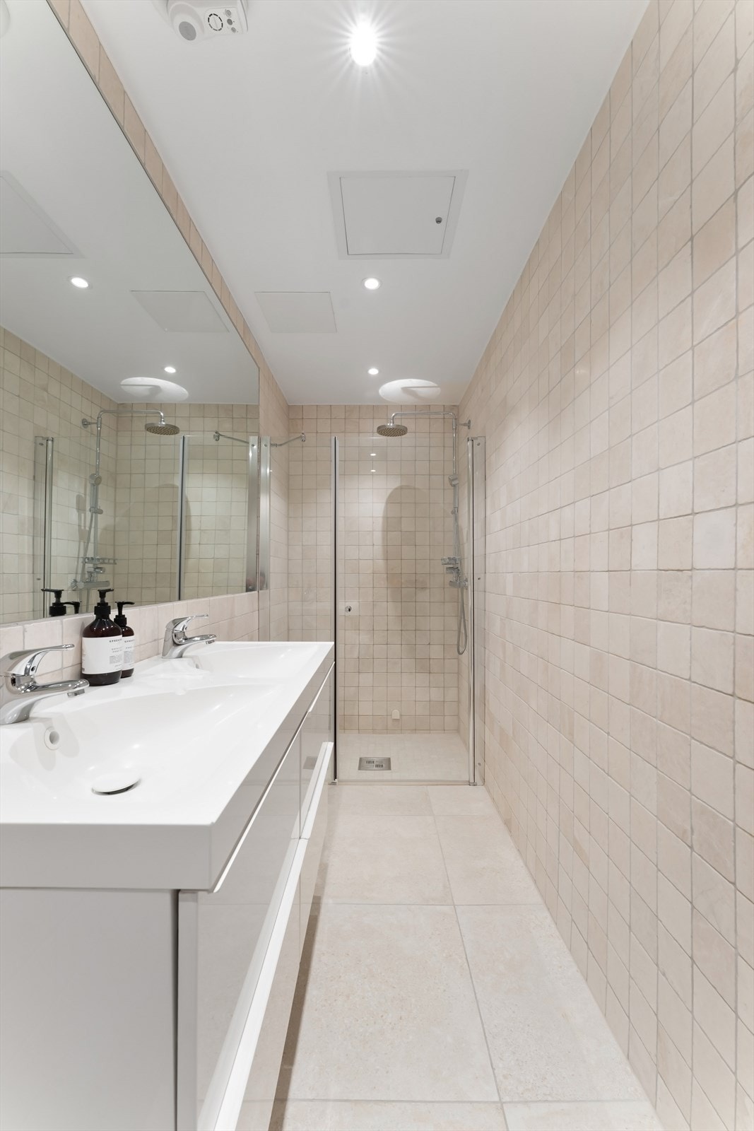 Lyst og pent bad med heldekkende dobbelservant med underskuffer og nedsenket dusjnisje med dusjvegg og dør i herdet glass. Galleribilde