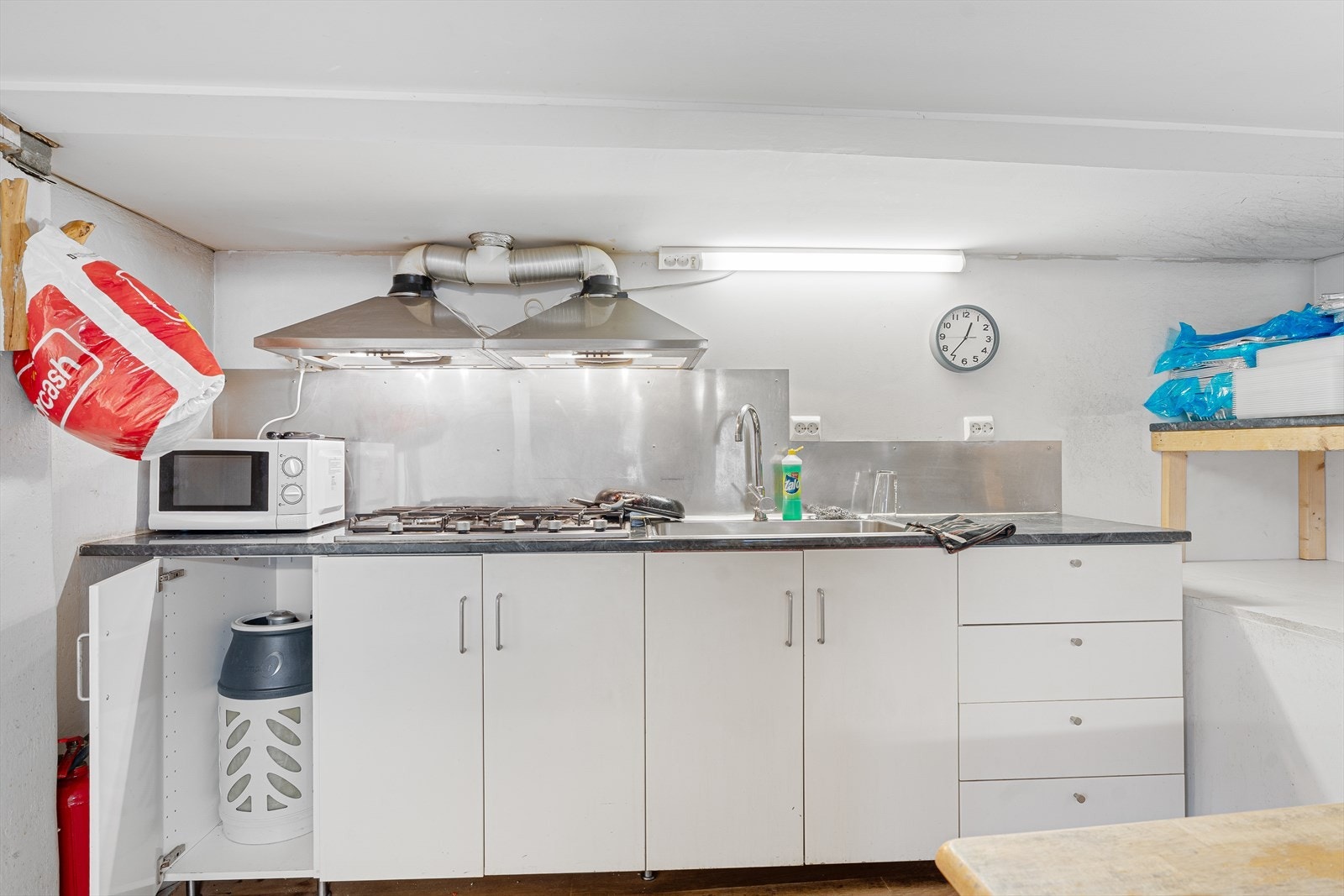 Kjøkkenet i kjelleren har enkel kjøkkeninnredning med slette fronter og laminat benkeplate Galleribilde