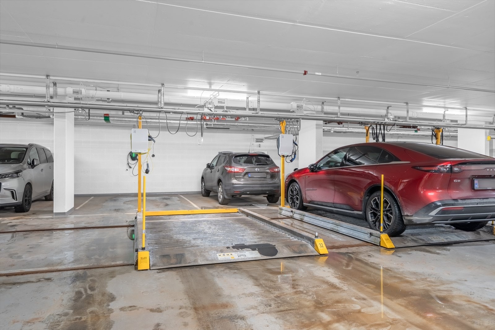 Garasjeanlegget har flere parkeringsplasser med moderne heissystem for effektiv utnyttelse av plassen. Galleribilde