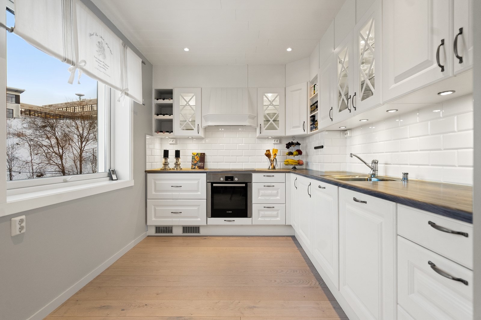 Lys kjøkkeninnredning fra JKE. Kjøkkenet er utstyrt med kjøleskuff, oppvaskmaskin, stekeovn og induksjonstopp. Det er ventilator med avtrekk ut. Galleribilde