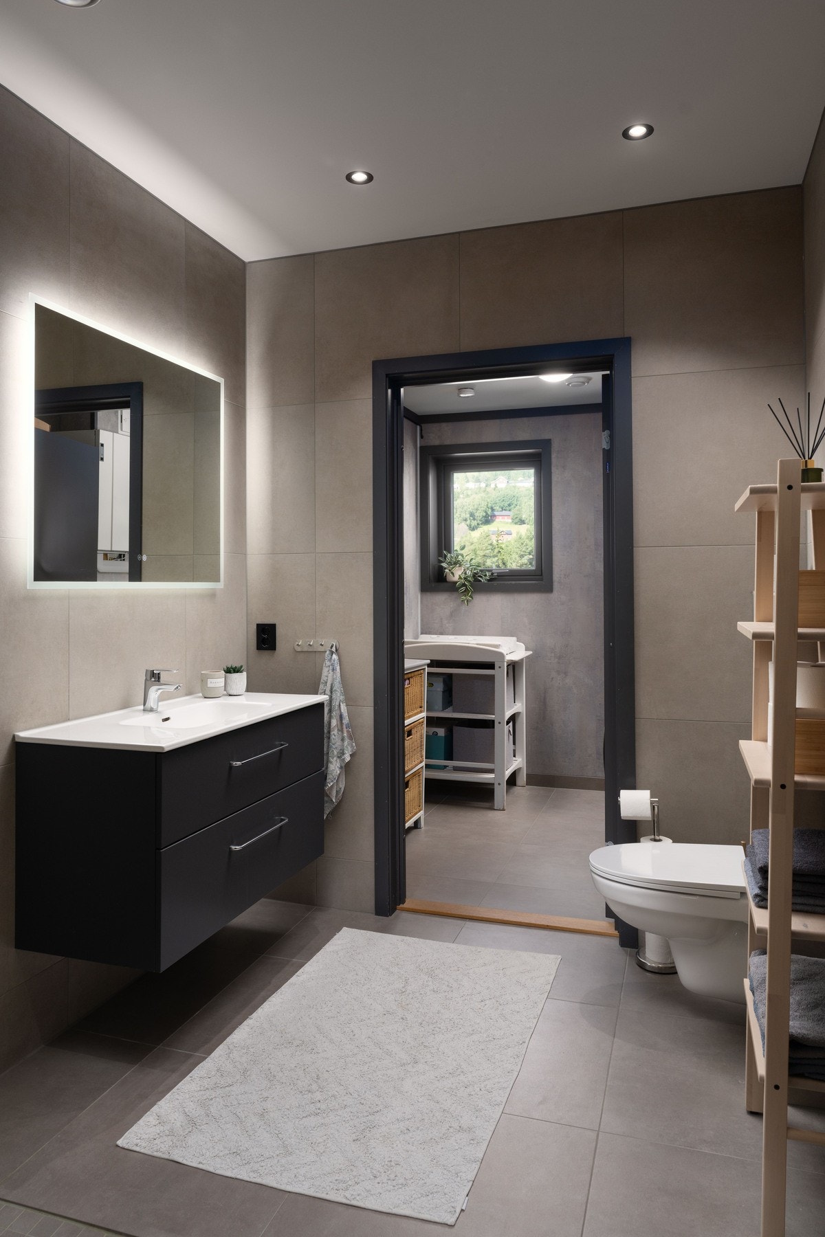 Bad med fliser på gulv og baderomsplater på vegg. Dør inn til vaskerom fra badet. Galleribilde