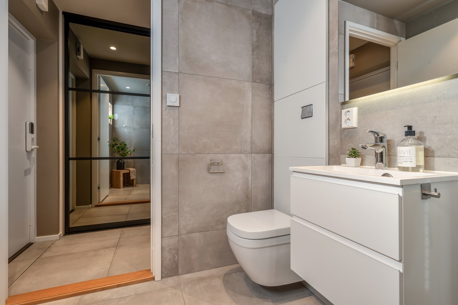 Plasseringen rett ved entreen gjør det enkelt å vaske av seg skitt og søle etter en dag i barnehagen, regn eller snø før man beveger seg inn i resten av boligen - en funksjonell og gjennomtenkt løsning for både familier og aktive par. Galleribilde