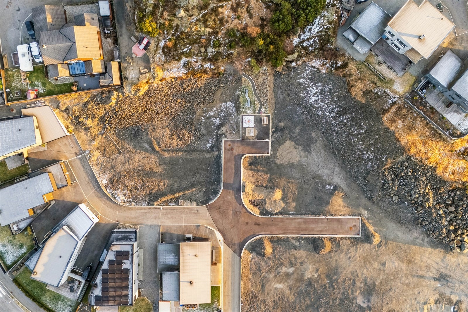 Dronebilde over tomteområdet som viser asfaltert adkomst, opparbeidede internveier og ferdigstilt infrastruktur. Galleribilde