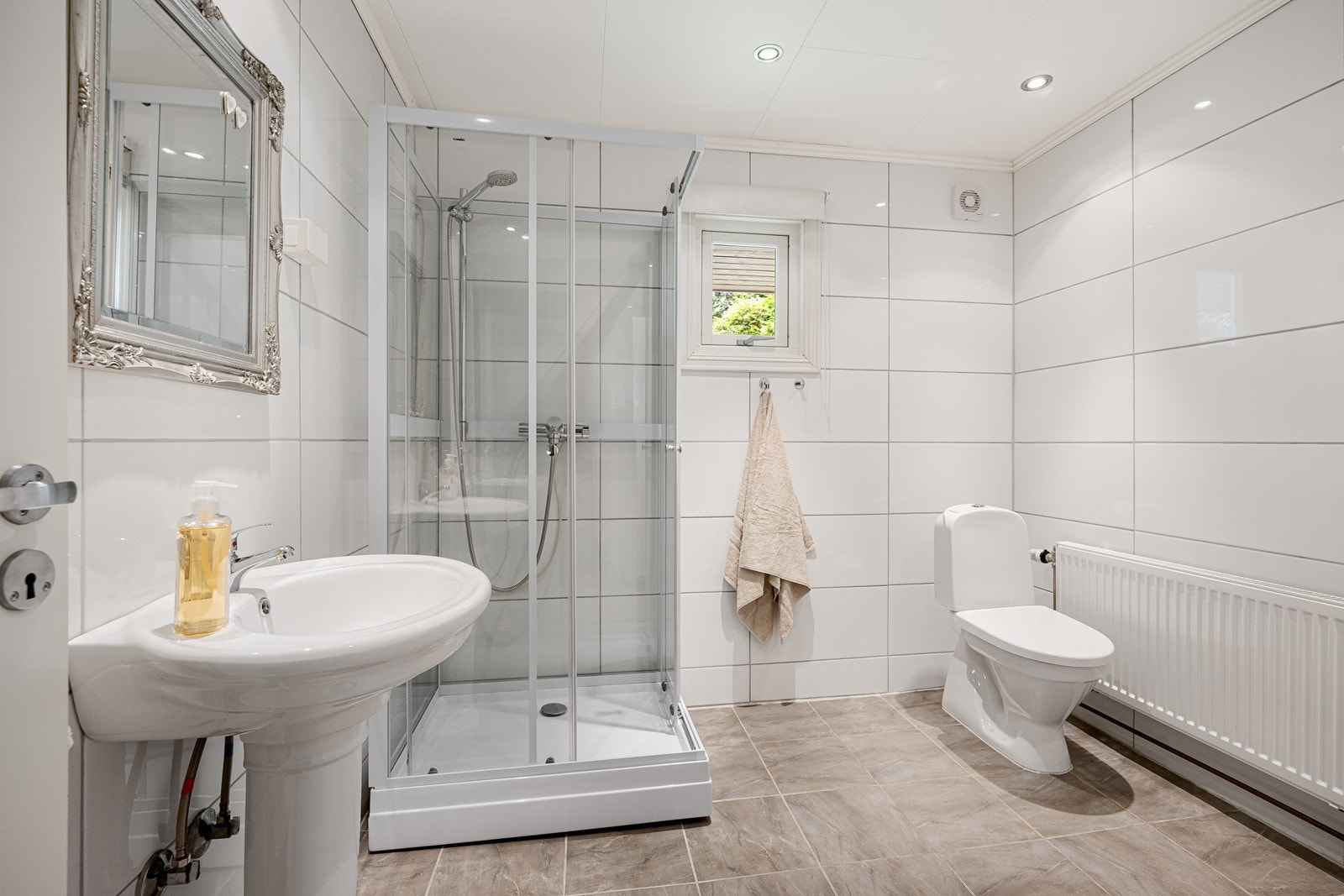 Her er det hvite fliser på veggene, downlights i himlingen og sandfargede fliser på gulv med elektrisk gulvvarme. Galleribilde