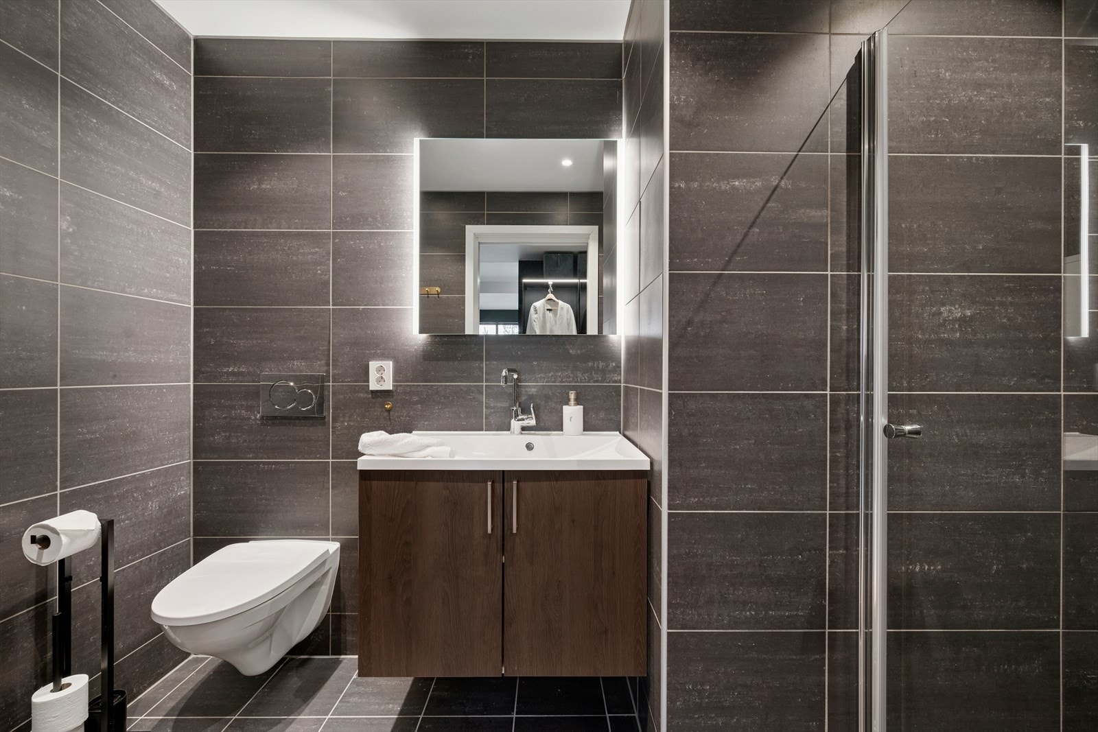 Badet tilknyttet hovedsoverommet er stilrent og helfliset med varmekabler for ekstra komfort. Galleribilde