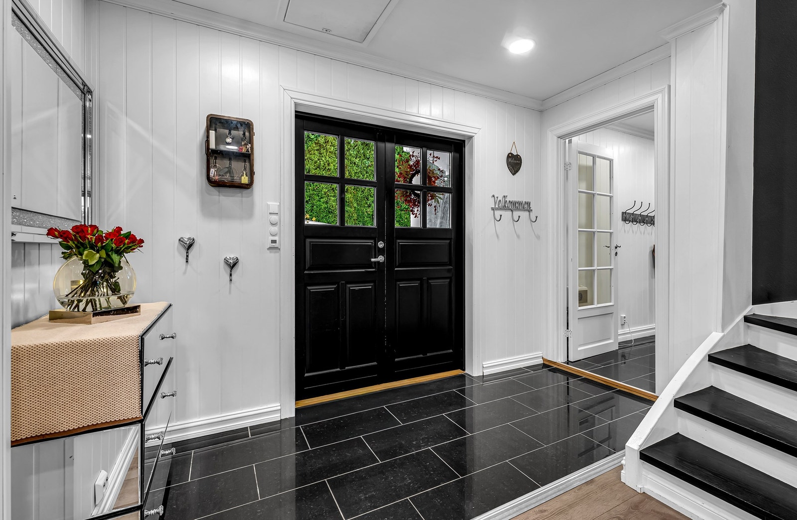 En representativ entré med mørke gulvfliser og doble inngangsdører. Galleribilde