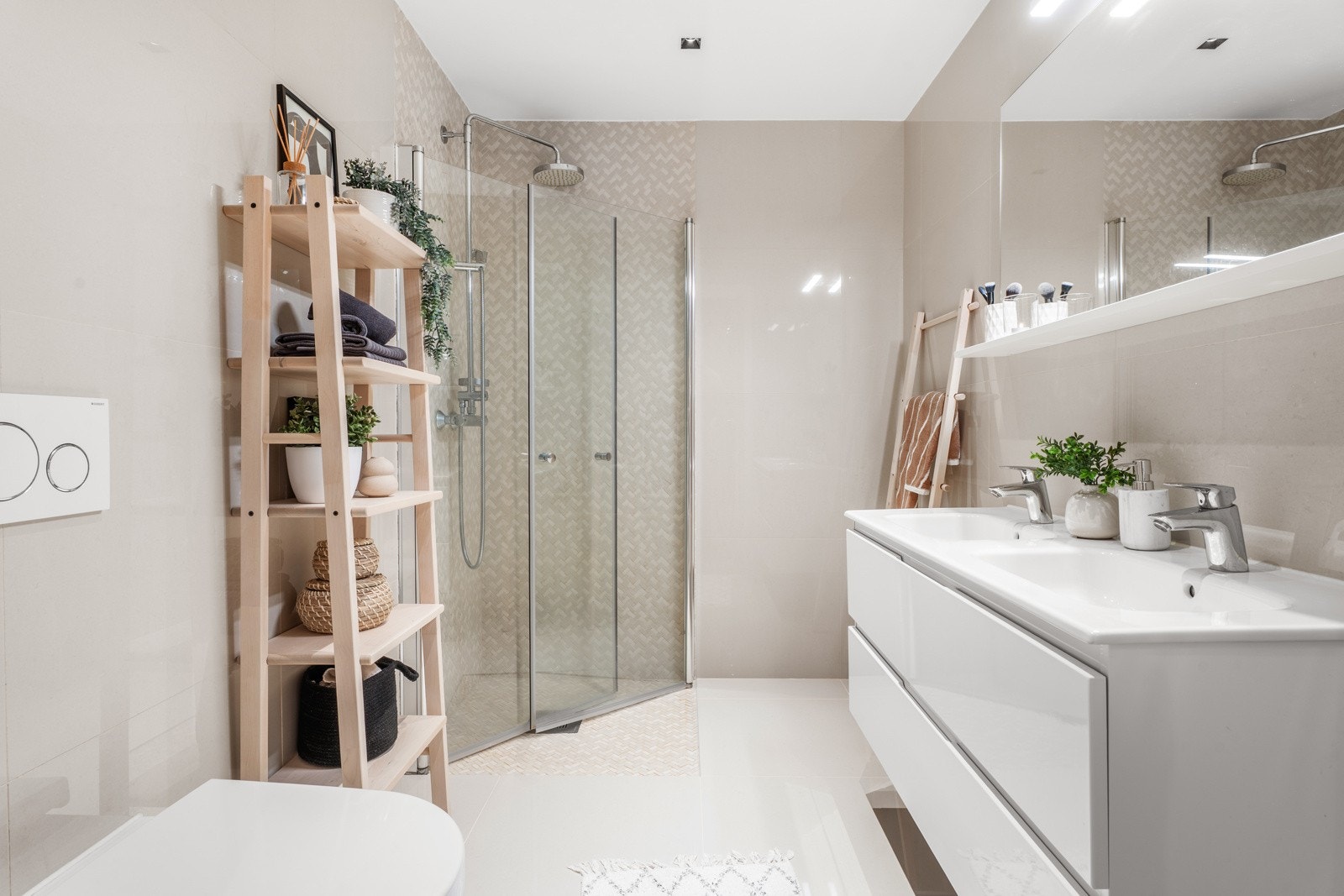 Stilrent baderom med varme fargetoner, dobbel servant og dusjhjørne med stilige fliser lagt i fiskebensmønster. Galleribilde