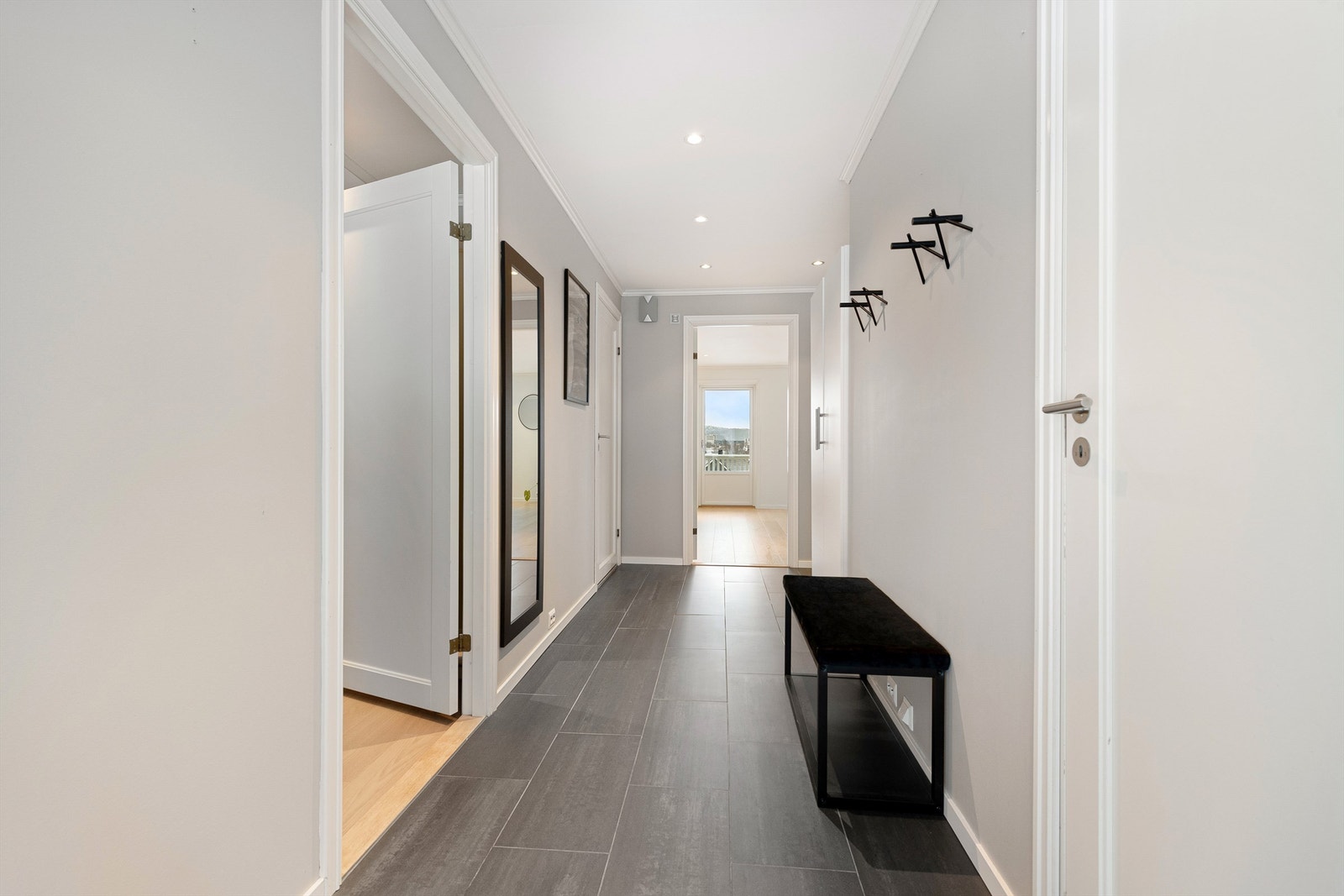 Lys og flislagt entre/gang med hvite profilerte innerdører og dør med glassfelt mot stue/kjøkken Galleribilde