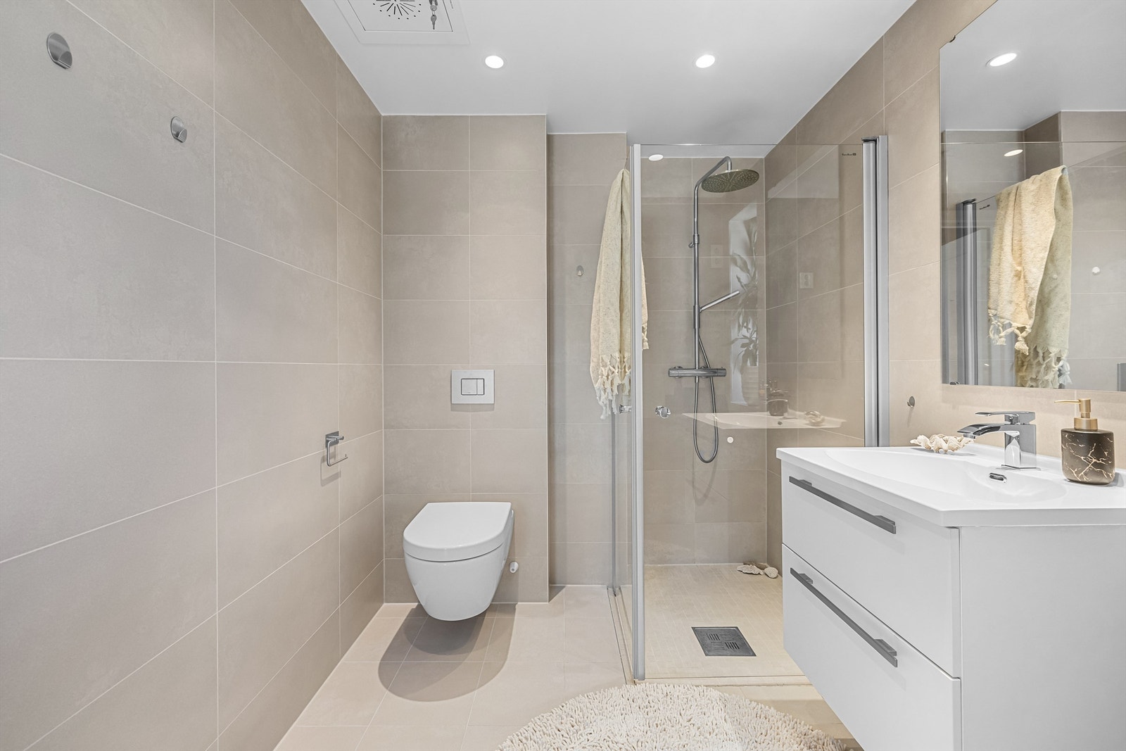 På badet finner du et dusjhjørne med regnfallsdusj og glassdører, vegghengt klosett, og servant nedfelt i innredning med skuffer. Det er opplegg for vaskemaskin. Galleribilde