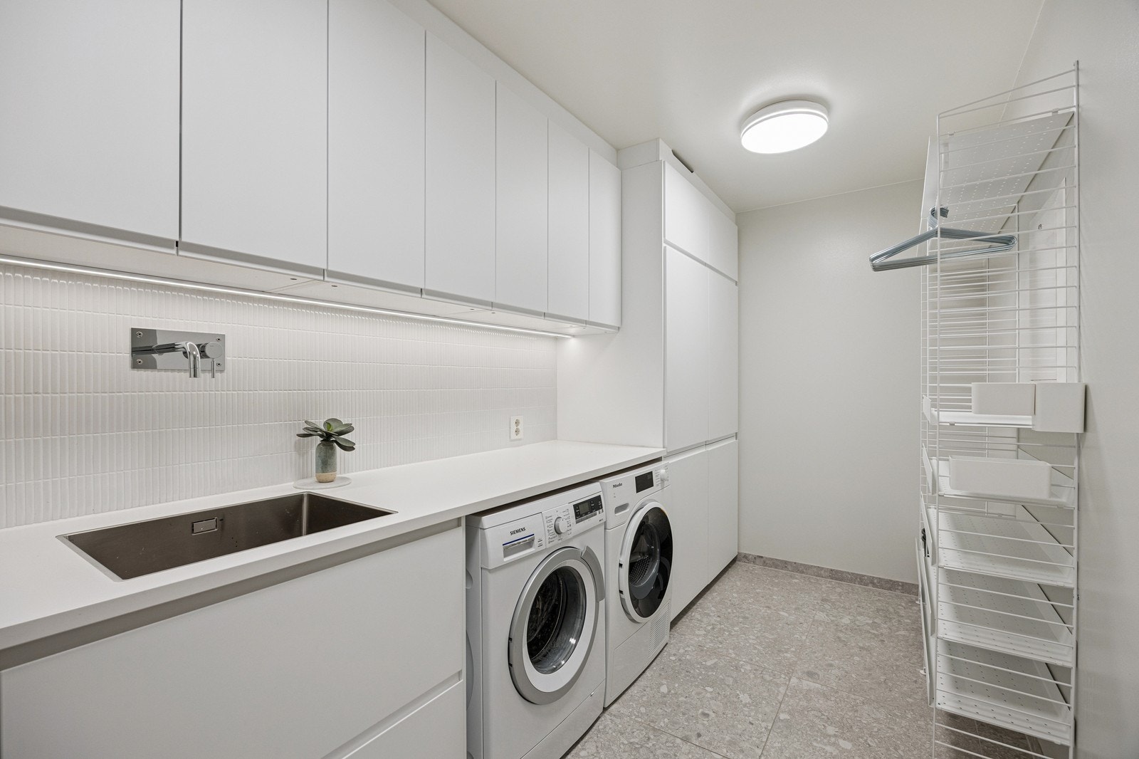 Vaskerom med tørketrommel og vaskemaskin. Her er det godt med skap- og benkeplass. Galleribilde