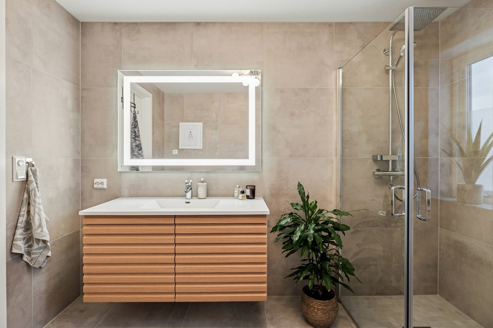 Vegghengt servant med en romslig benkeplate, toppet med et stort speil med integrert lys som gir god belysning. Galleribilde