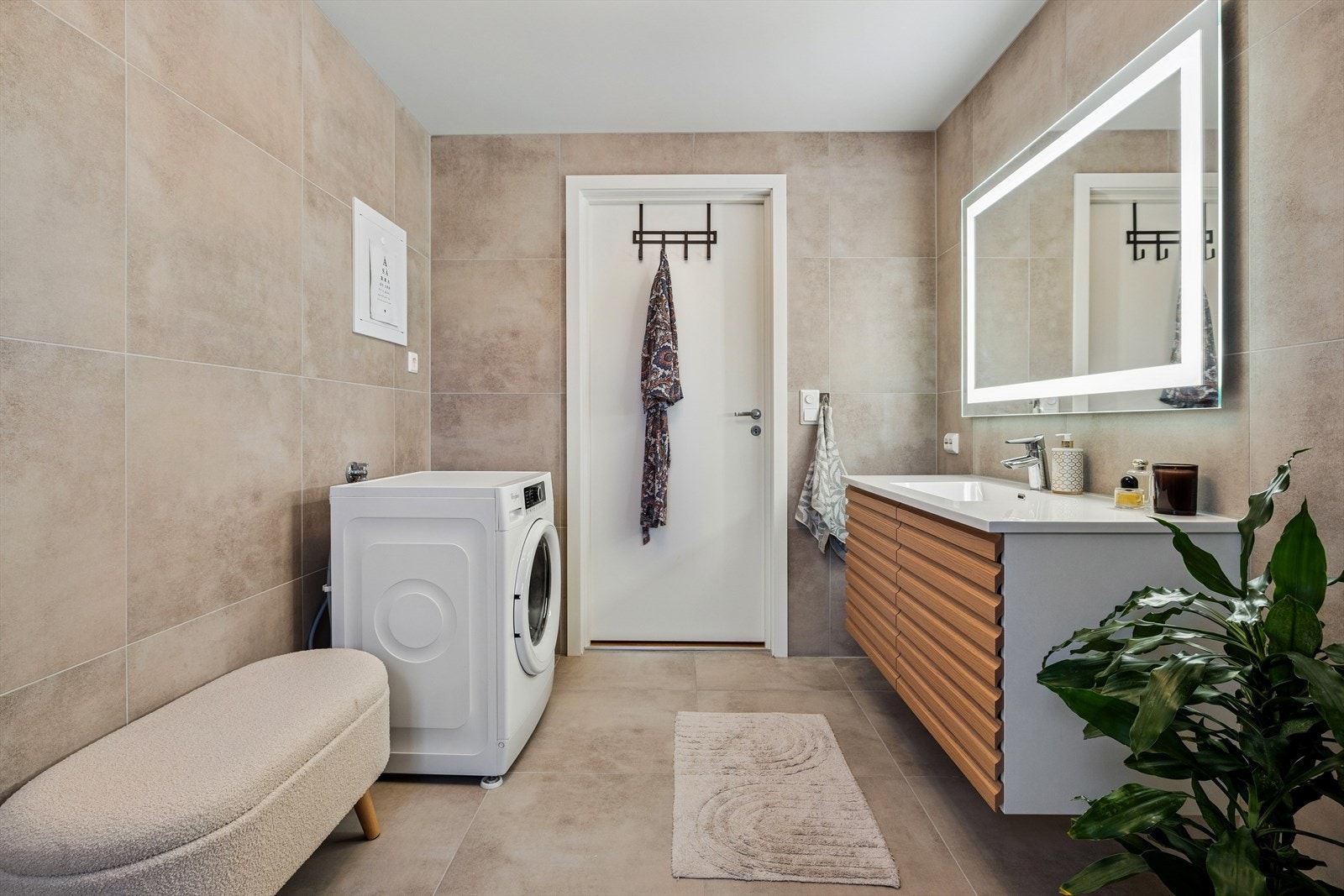 Baderomsinnredningen er bestående av vegghengt toalett, dusjhjørne og vask med speil over. Det er i tillegg montert opplegg for vaskemaskin. Galleribilde