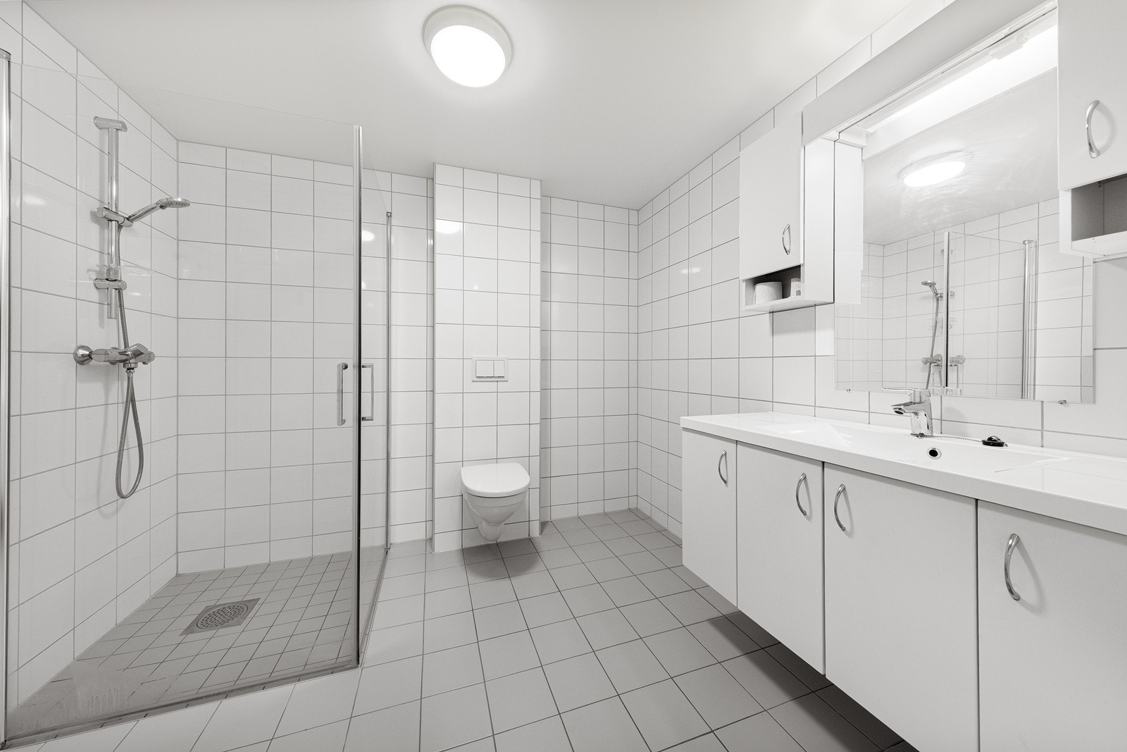 Badet er romslig og innredet i lyse farger med fliser på veggene og malt tak. Gulvet er flislagt og har vannbåren gulvvarme. Galleribilde