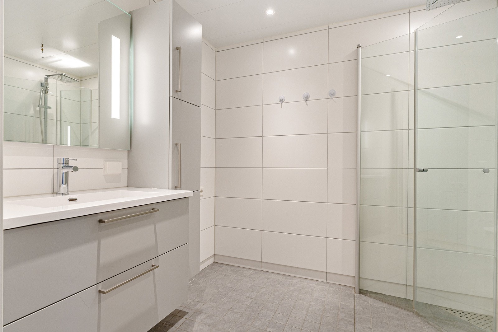 Det ca. 4,5 kvm store badet er stilrent innredet med delikate fliser på vegger og gulv. Galleribilde