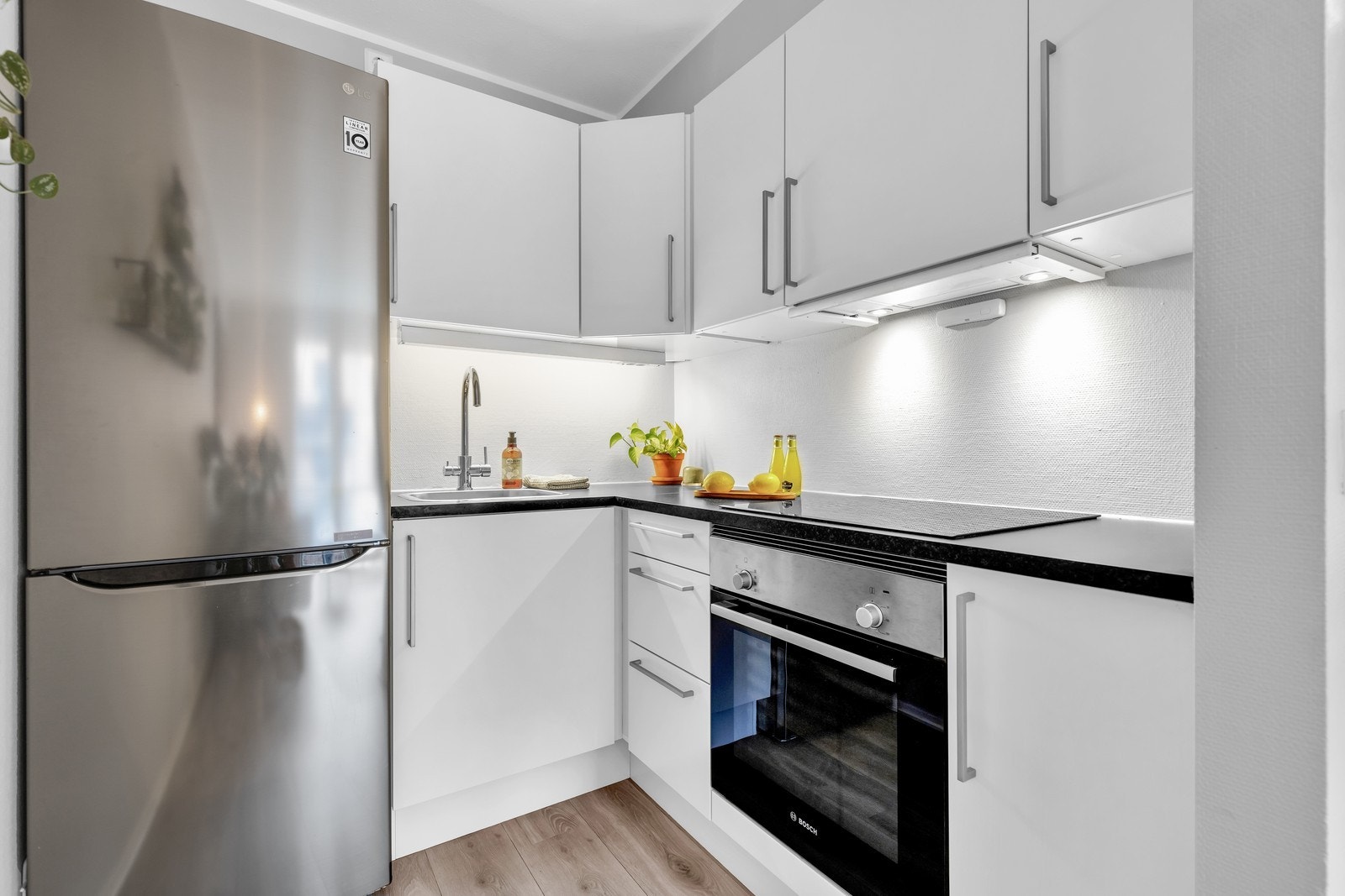 Kjøkken har lyse slette fronter og integrert steketopp/komfyr. Galleribilde