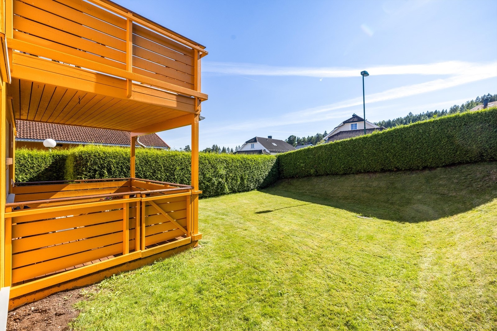 Fra verandaen er det adkomst ut til felles plenareal for tomannsboligen som også er fint skjermet med vintergrønn hekk. Galleribilde