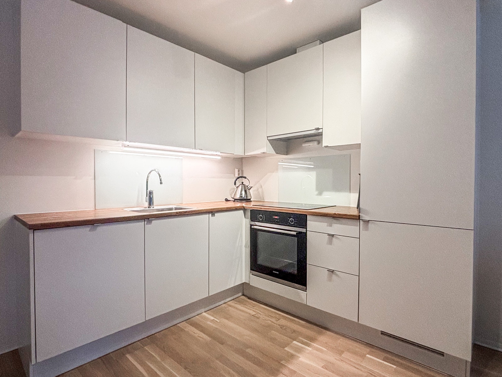 Flott kjøkken med moderne slette fronter og integrerte hvitevarer. Galleribilde