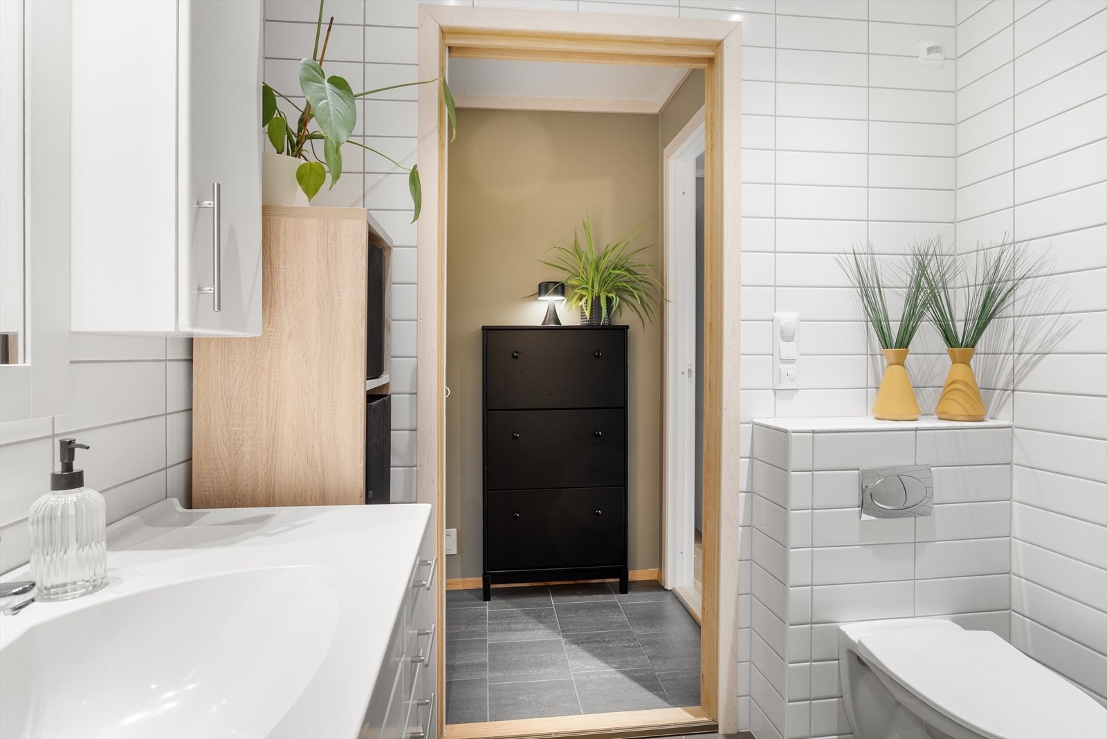 Badet er innredet med hvit baderomsinnredning med heldekkende servant, vegghengt toalett og dusjnisje med glassdører Galleribilde