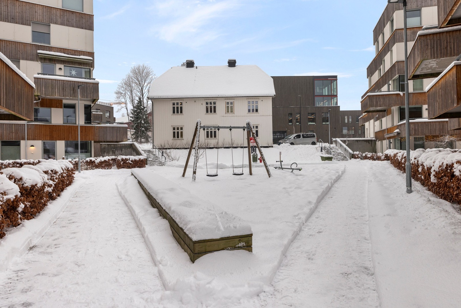 Pent opparbeidet tomt med plen, sittegrupper, lekeplass, vei og parkeringsareal Galleribilde