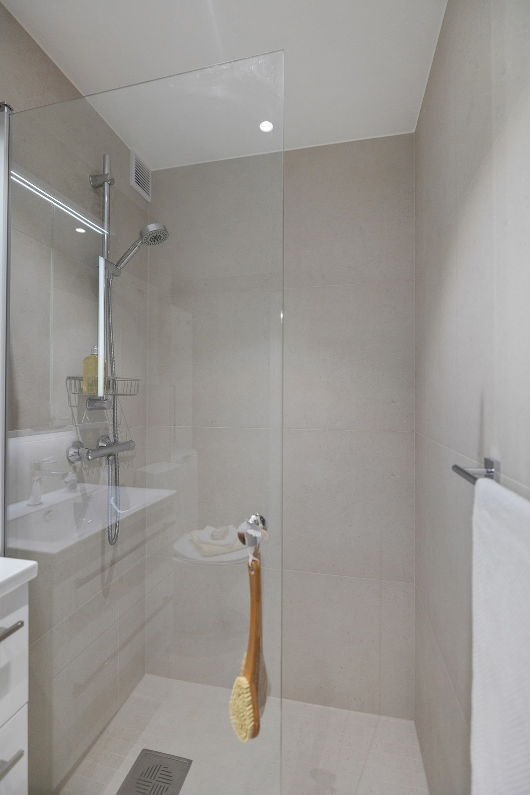 Moderne innredning med dusjnisje med glassdør tilkoblet hånddusj samt gulvstående toalett. Galleribilde