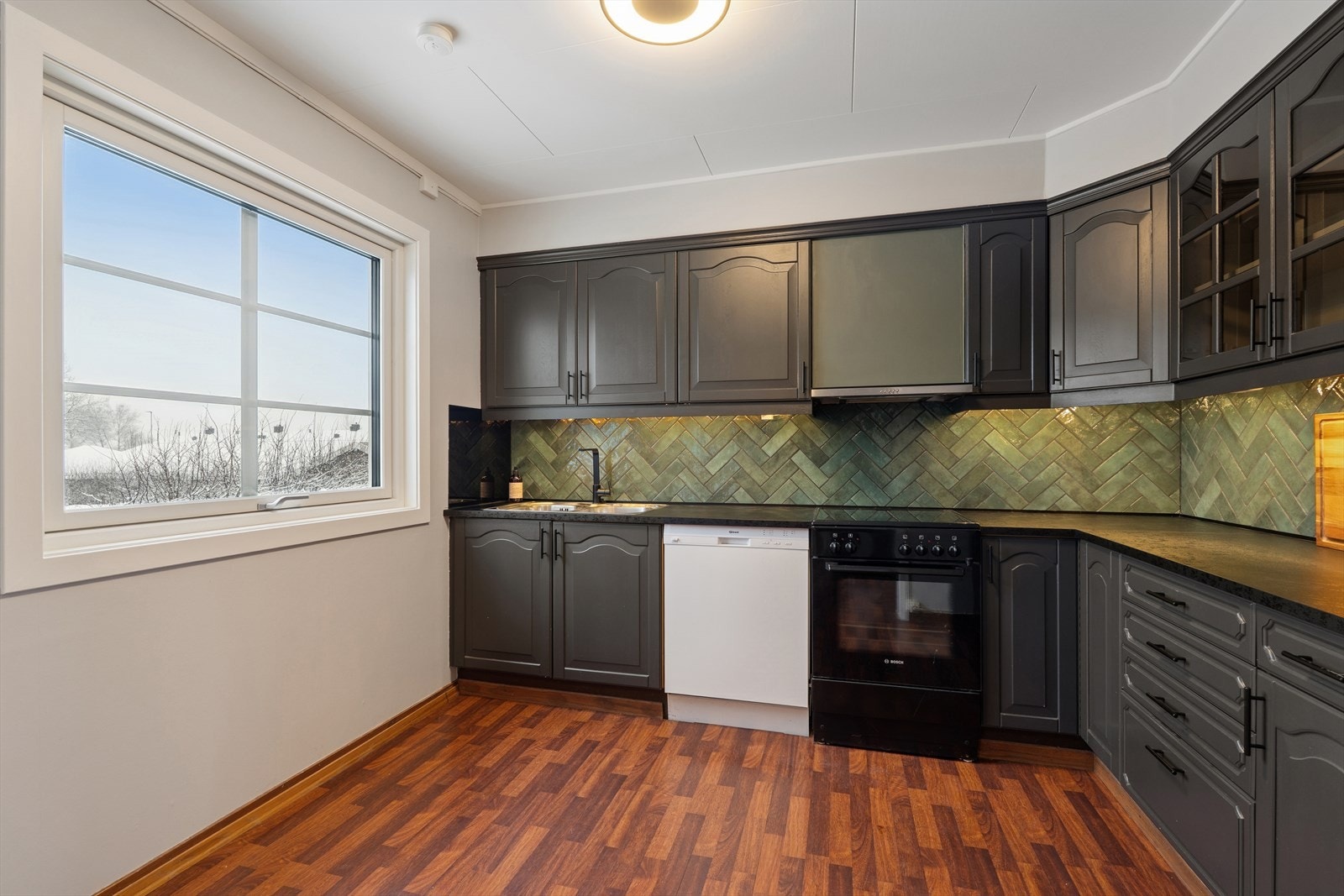 Romslig kjøkken med god benkplass og stort vindu som gir naturlig lys Galleribilde