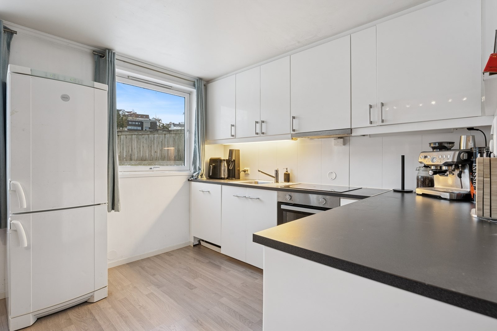 Kjøkkenet i leiligheten har en innredning med glatte fronter og en benkeplate av laminat. Galleribilde