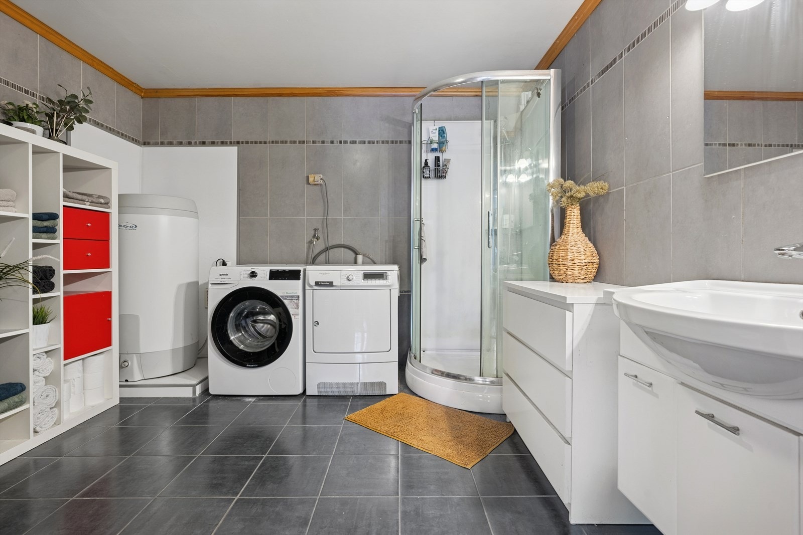 Badet i kjellerleiligheten er innredet med en nedfelt servant, et vegghengt toalett, et dusjkabinett og har opplegg for vaskemaskin. Galleribilde