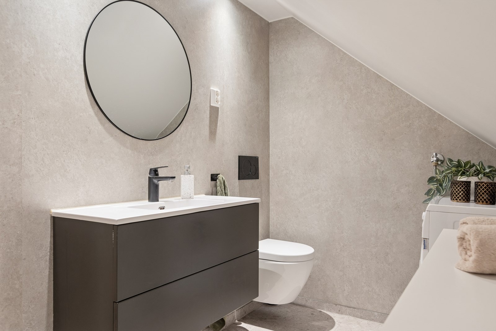 Videre er badet utstyrt med blant annet vegghengt klosett, servant med oppbevaring og opplegg for vaskemaskin. Galleribilde